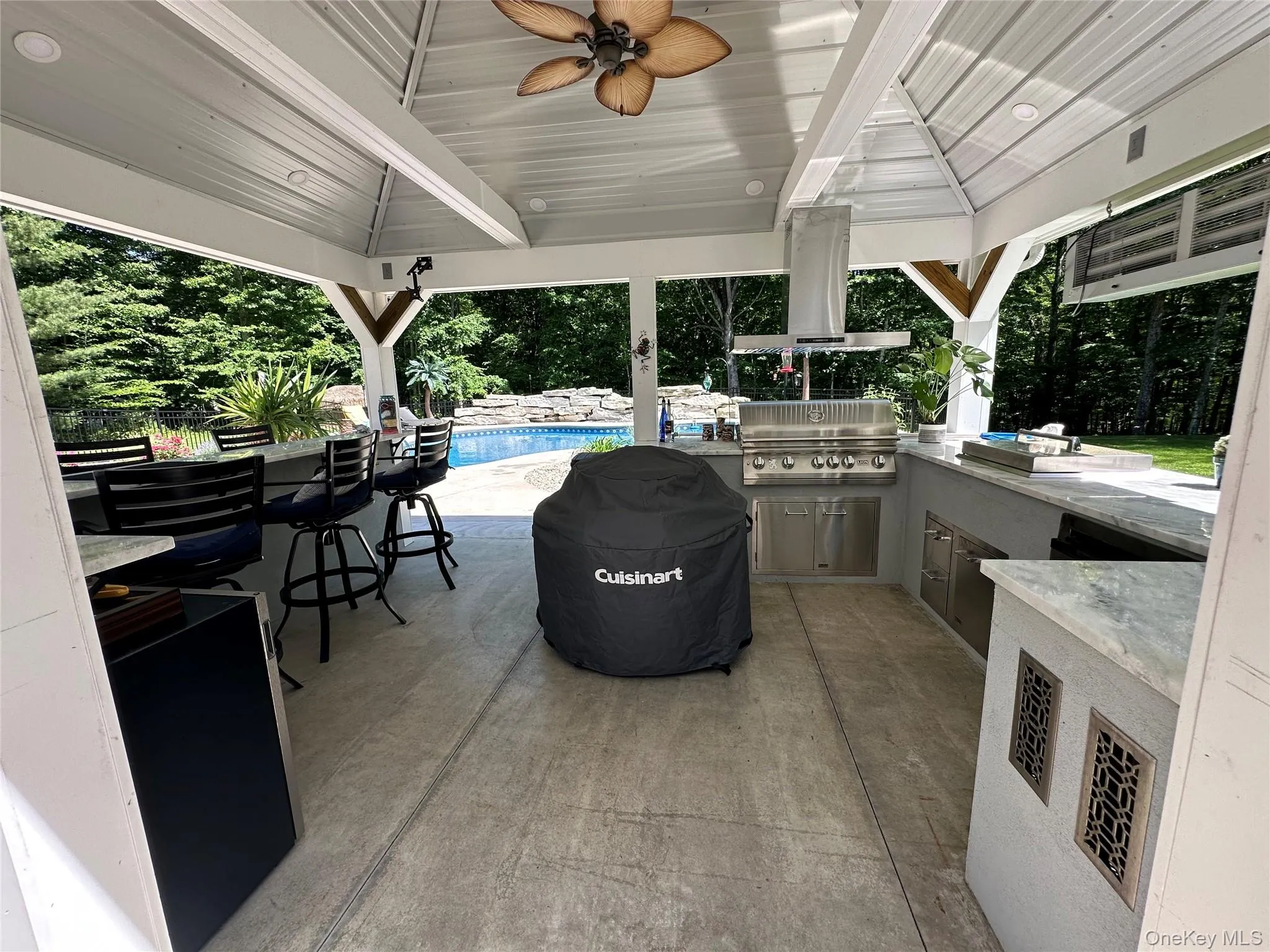 Covered outdoor kitchen featuring a built-in stainless steel grill, range hood, and cabinetry Covered outdoor kitchen featuring a built-in stainless steel grill, range hood, and cabinetry
