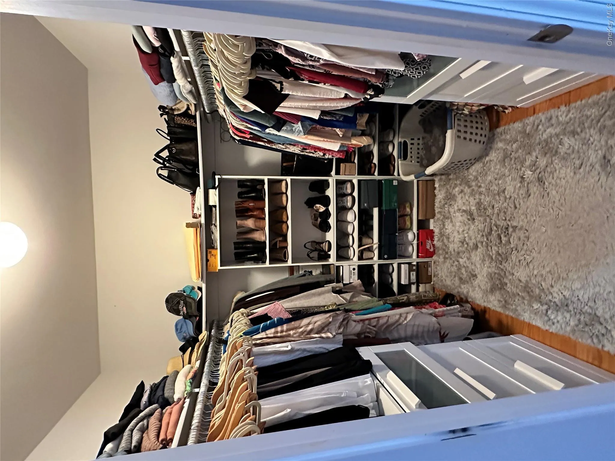 Walk-in closet featuring hardwood flooring, built-in shelving, hanging rods, and integrated drawer storage Walk-in closet featuring hardwood flooring, built-in shelving, hanging rods, and integrated drawer storage