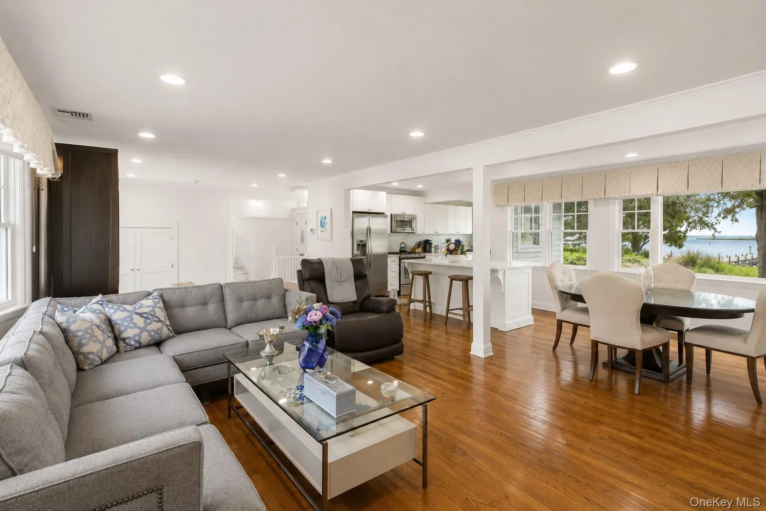 Open-concept living area featuring rich wood-finish flooring, recessed lighting, and expansive windows Open-concept living area featuring rich wood-finish flooring, recessed lighting, and expansive windows