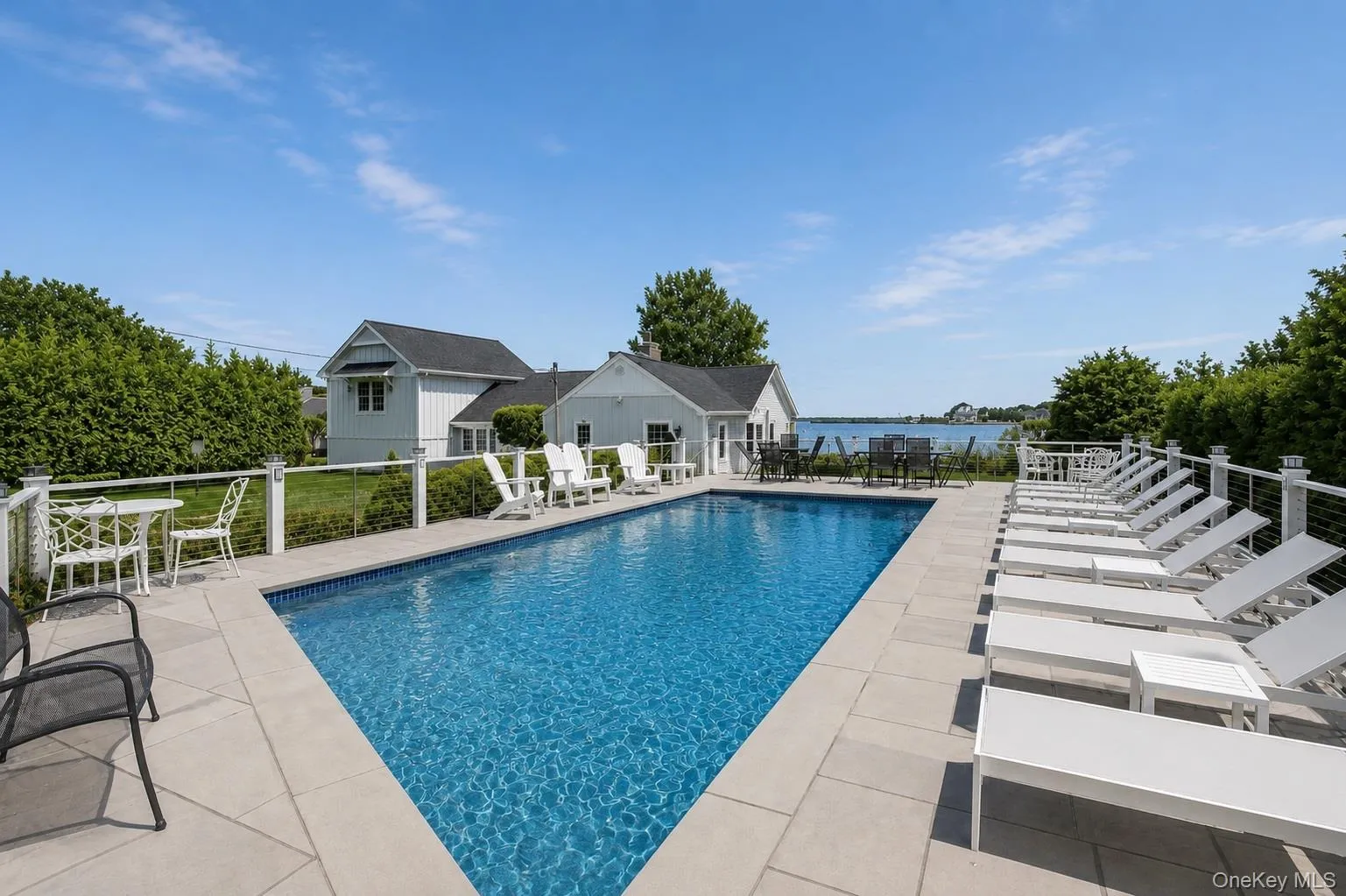 Rectangular in-ground pool surrounded by light-colored paving stones Rectangular in-ground pool surrounded by light-colored paving stones