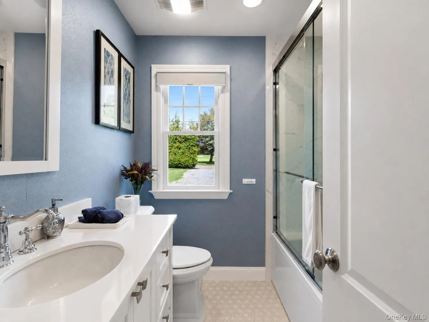 Bathroom featuring a single vanity with a white countertop and undermount sink, chrome faucet, and white cabinetry Bathroom featuring a single vanity with a white countertop and undermount sink, chrome faucet, and white cabinetry