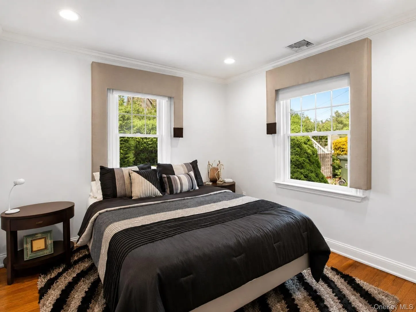 Bright bedroom featuring hardwood flooring, white walls, and recessed lighting Bright bedroom featuring hardwood flooring, white walls, and recessed lighting