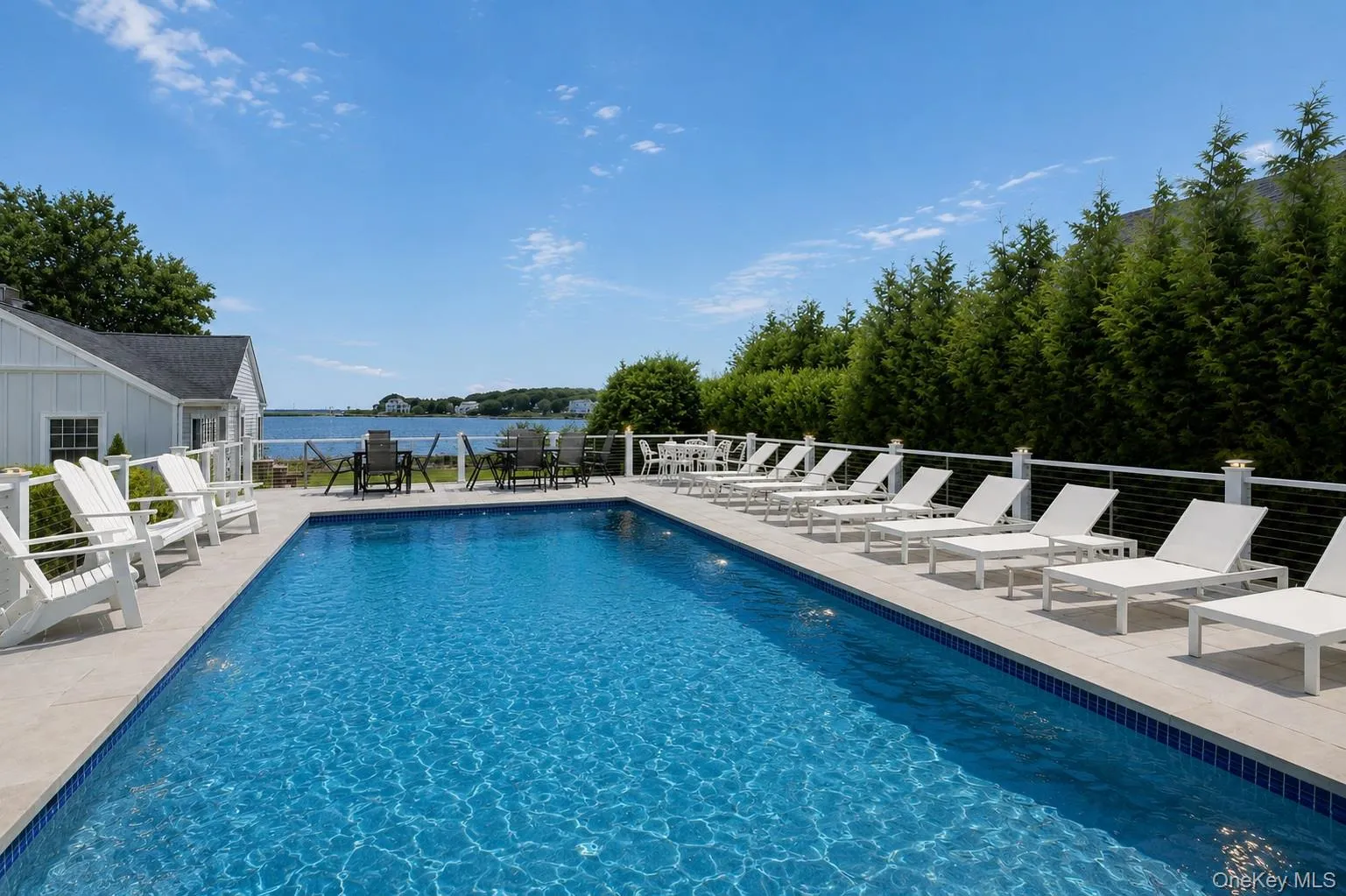 Outdoor swimming pool featuring a light-colored tile surround and a water view Outdoor swimming pool featuring a light-colored tile surround and a water view