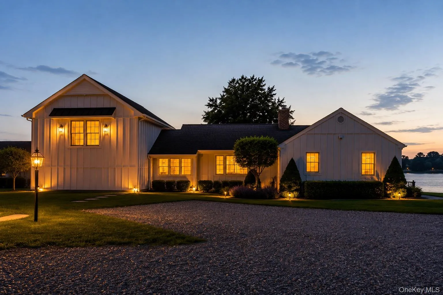 White board-and-batten exterior with black trim windows, a dark shingle roof, and a gravel driveway White board-and-batten exterior with black trim windows, a dark shingle roof, and a gravel driveway