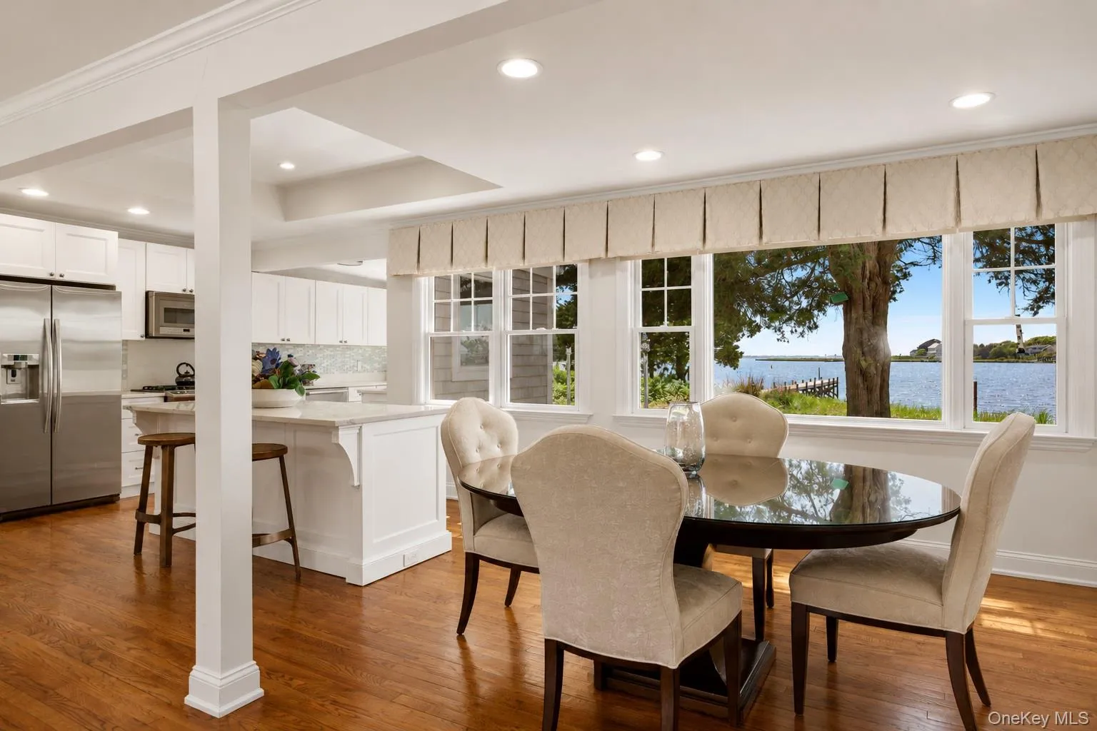 Dining area featuring expansive windows, water scenery, wood-finish flooring, recessed lighting, and crown molding Dining area featuring expansive windows, water scenery, wood-finish flooring, recessed lighting, and crown molding