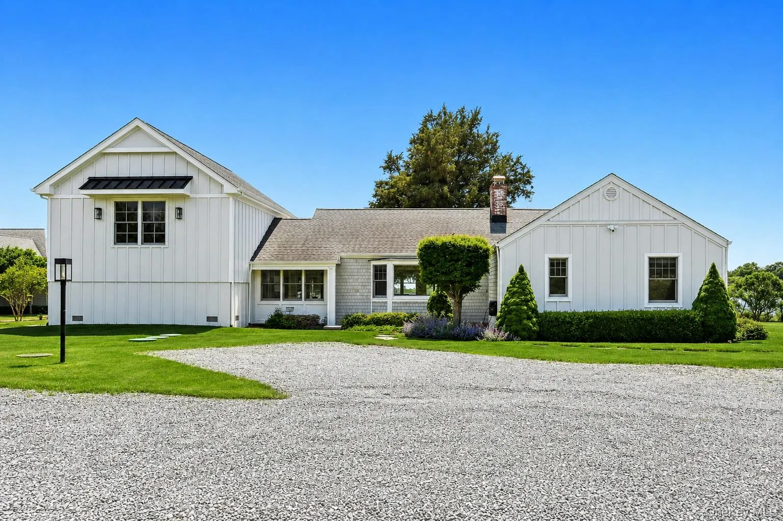 Gravel driveway leading to a multi-gable exterior with a board and batten facade and horizontal siding Gravel driveway leading to a multi-gable exterior with a board and batten facade and horizontal siding
