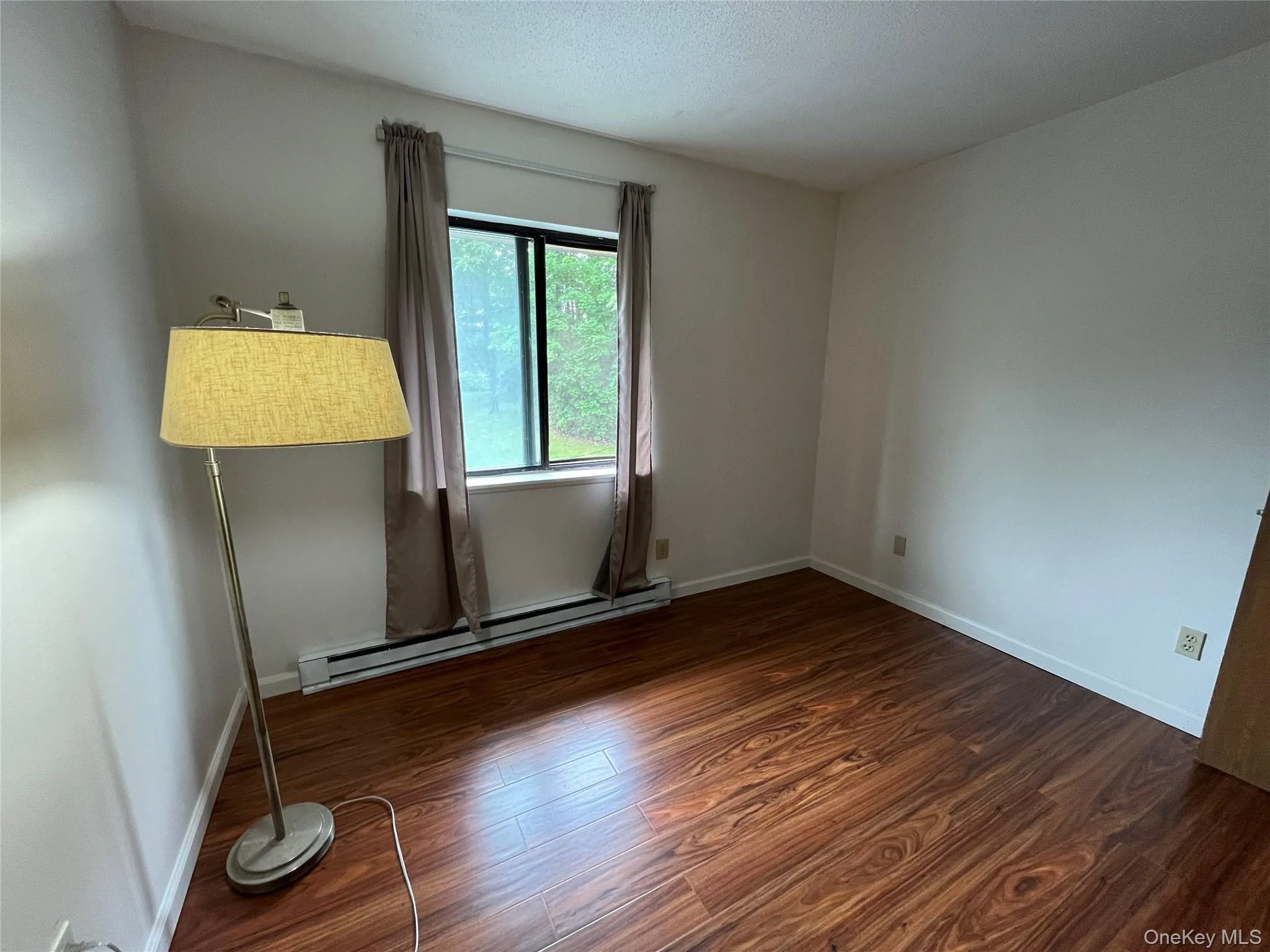 Unfurnished room featuring a baseboard heating unit and wood finished floors Unfurnished room featuring a baseboard heating unit and wood finished floors