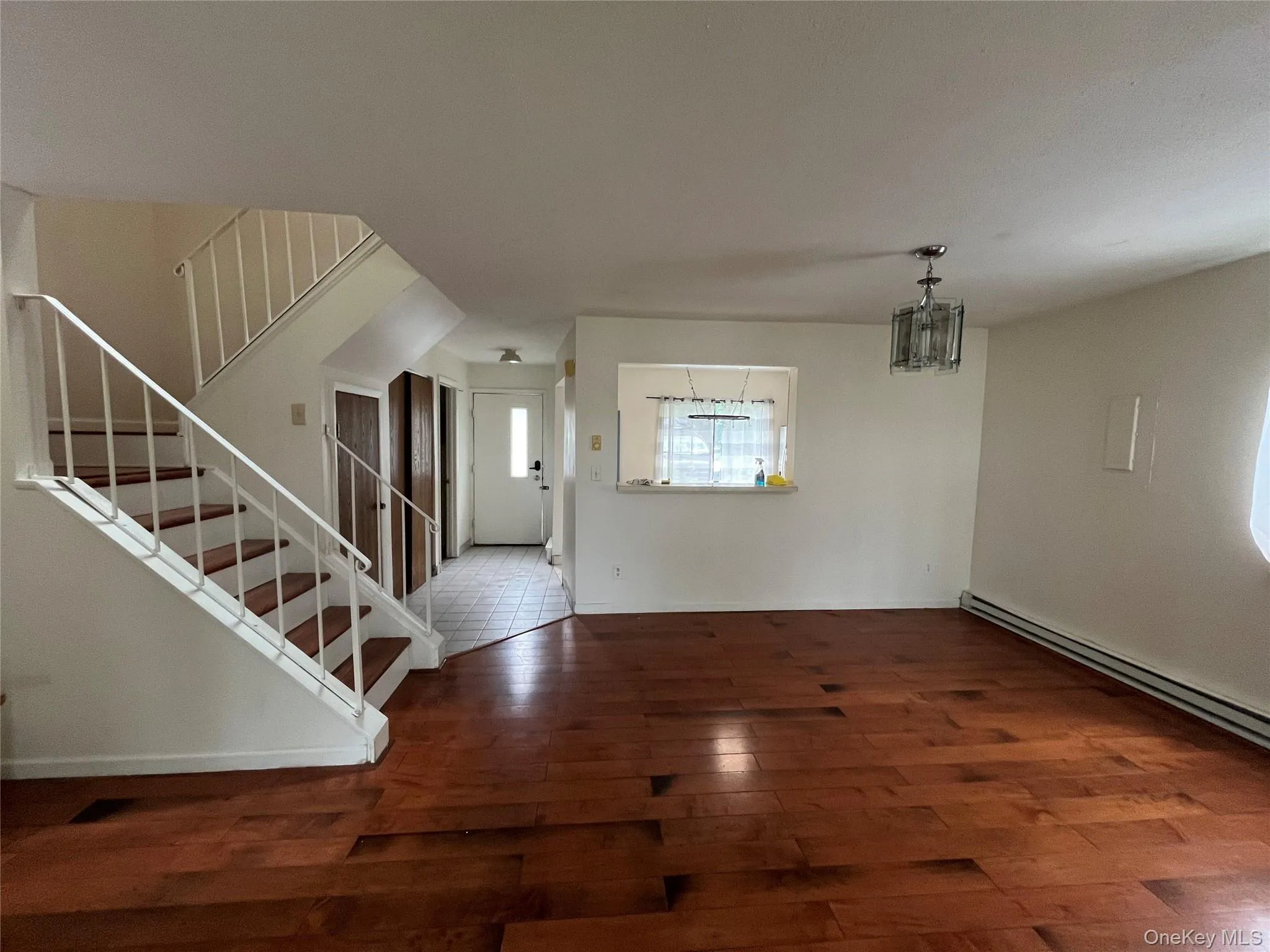 Entryway featuring wood finished floors, a baseboard radiator, stairs, and a chandelier Entryway featuring wood finished floors, a baseboard radiator, stairs, and a chandelier