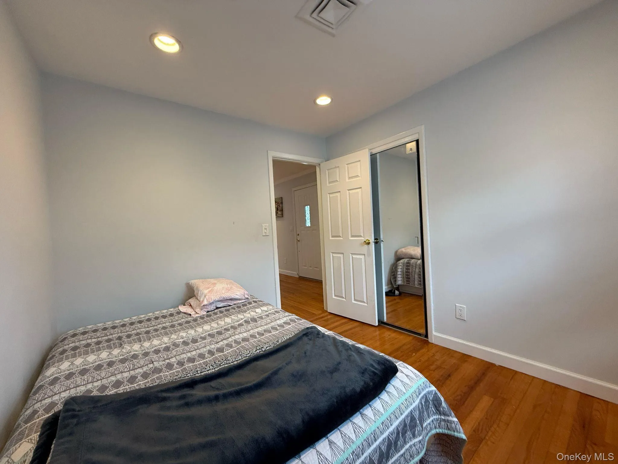 Bedroom featuring recessed lighting, baseboards, visible vents, a closet, and wood finished floors Bedroom featuring recessed lighting, baseboards, visible vents, a closet, and wood finished floors