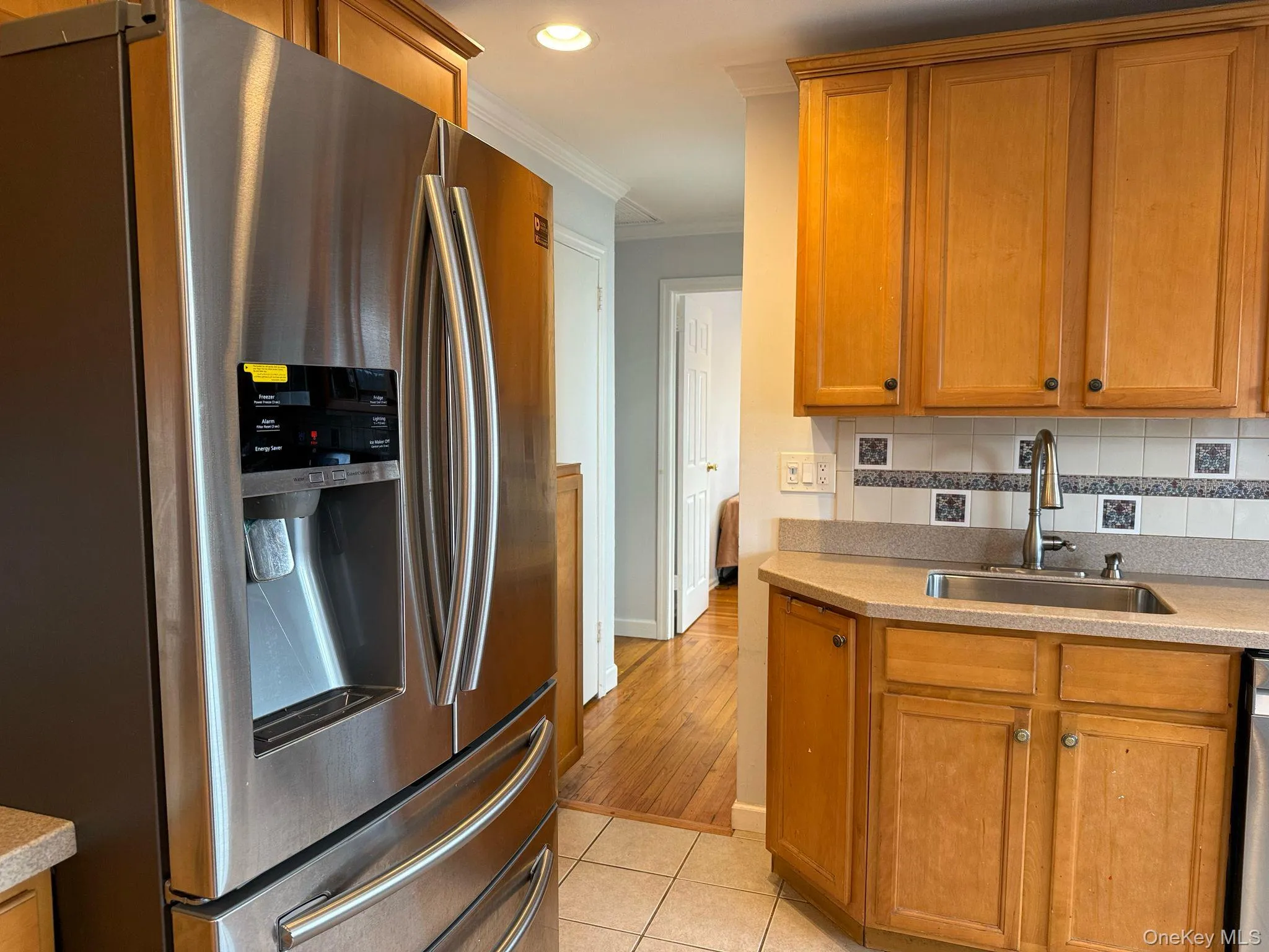 Kitchen featuring light tile patterned flooring, crown molding, stainless steel appliances, tasteful backsplash, and a sink Kitchen featuring light tile patterned flooring, crown molding, stainless steel appliances, tasteful backsplash, and a sink
