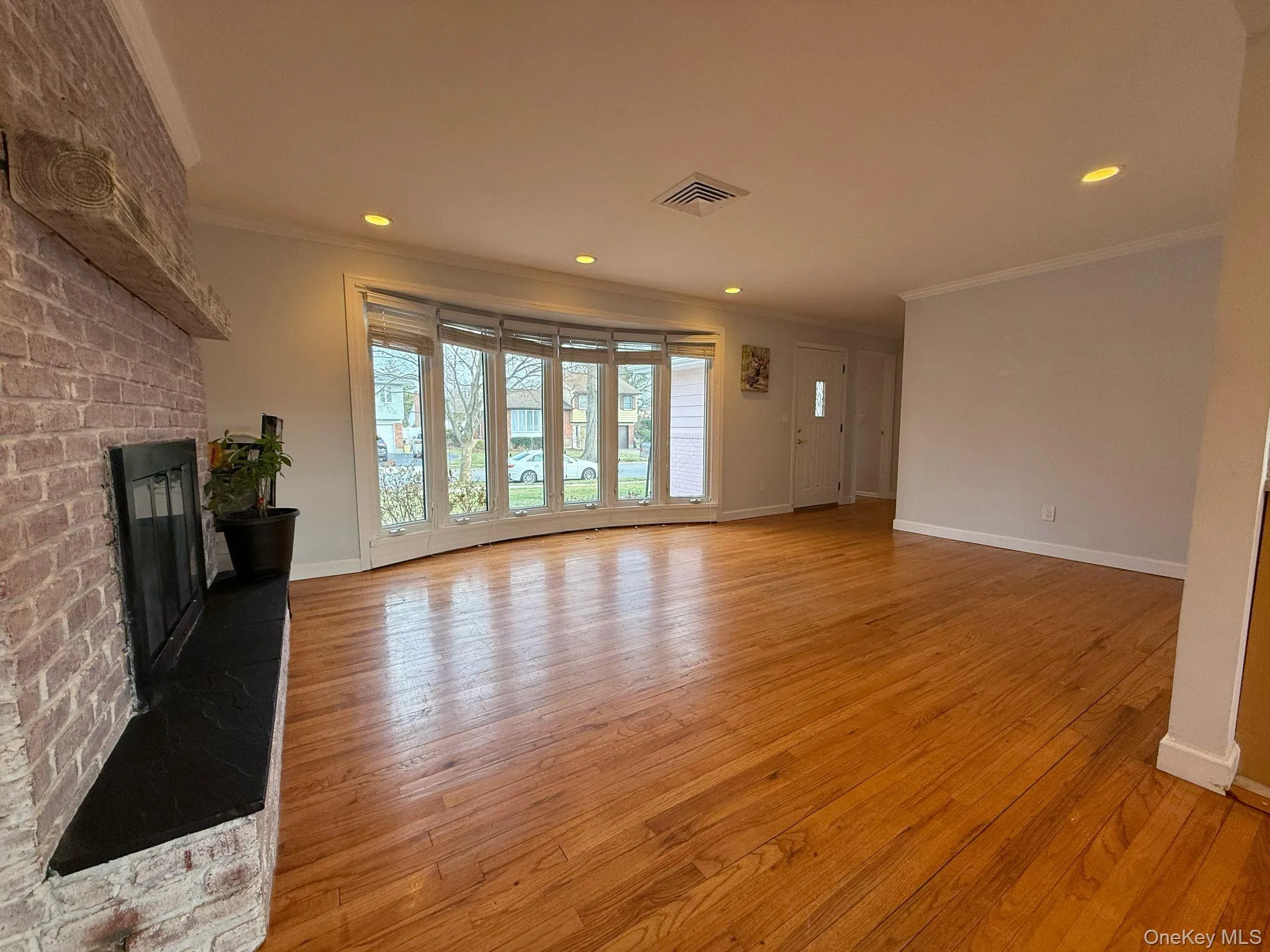 Unfurnished living room featuring ornamental molding, a fireplace, and light wood-type flooring Unfurnished living room featuring ornamental molding, a fireplace, and light wood-type flooring