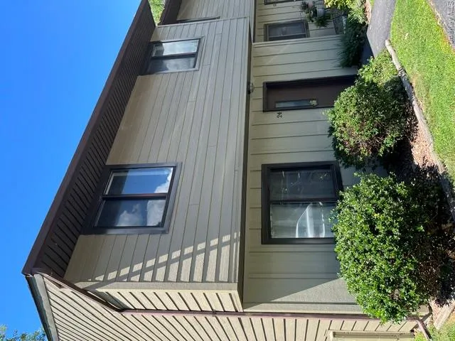 Multi-level facade with light-toned horizontal siding and dark trim windows Multi-level facade with light-toned horizontal siding and dark trim windows