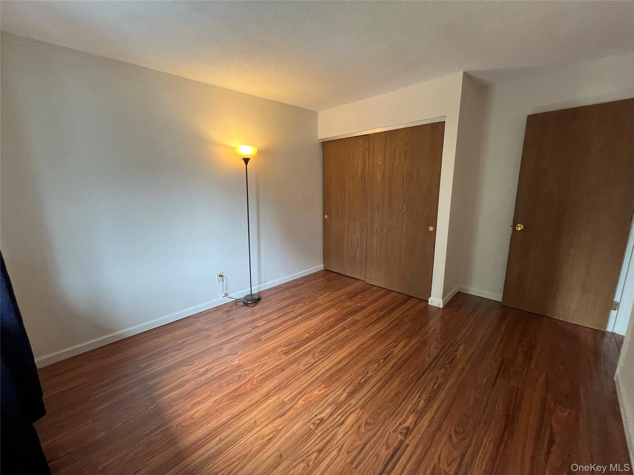 Unfurnished bedroom featuring wood finished floors and a closet Unfurnished bedroom featuring wood finished floors and a closet