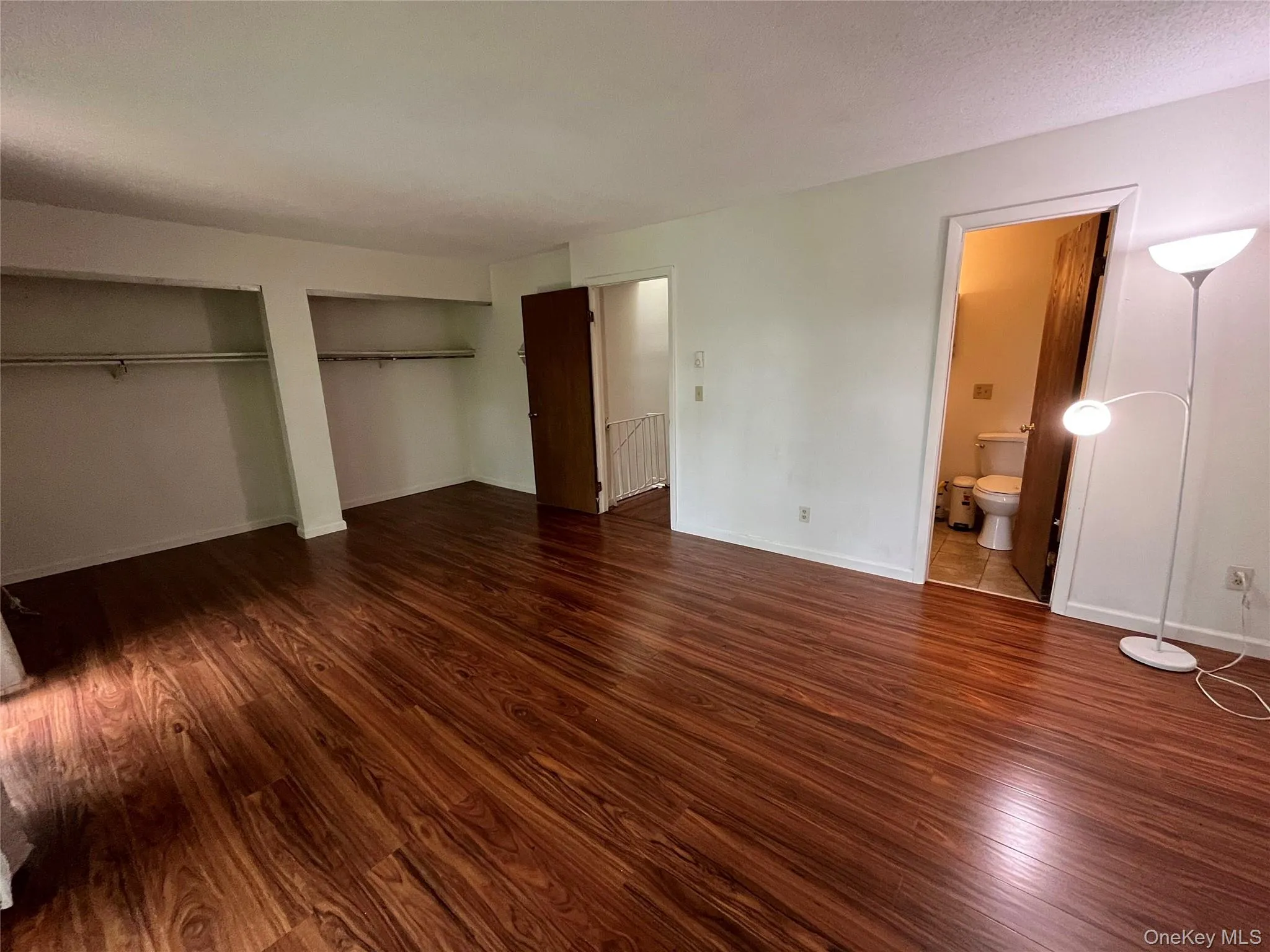 Unfurnished bedroom featuring wood finished floors, multiple closets, and ensuite bath Unfurnished bedroom featuring wood finished floors, multiple closets, and ensuite bath