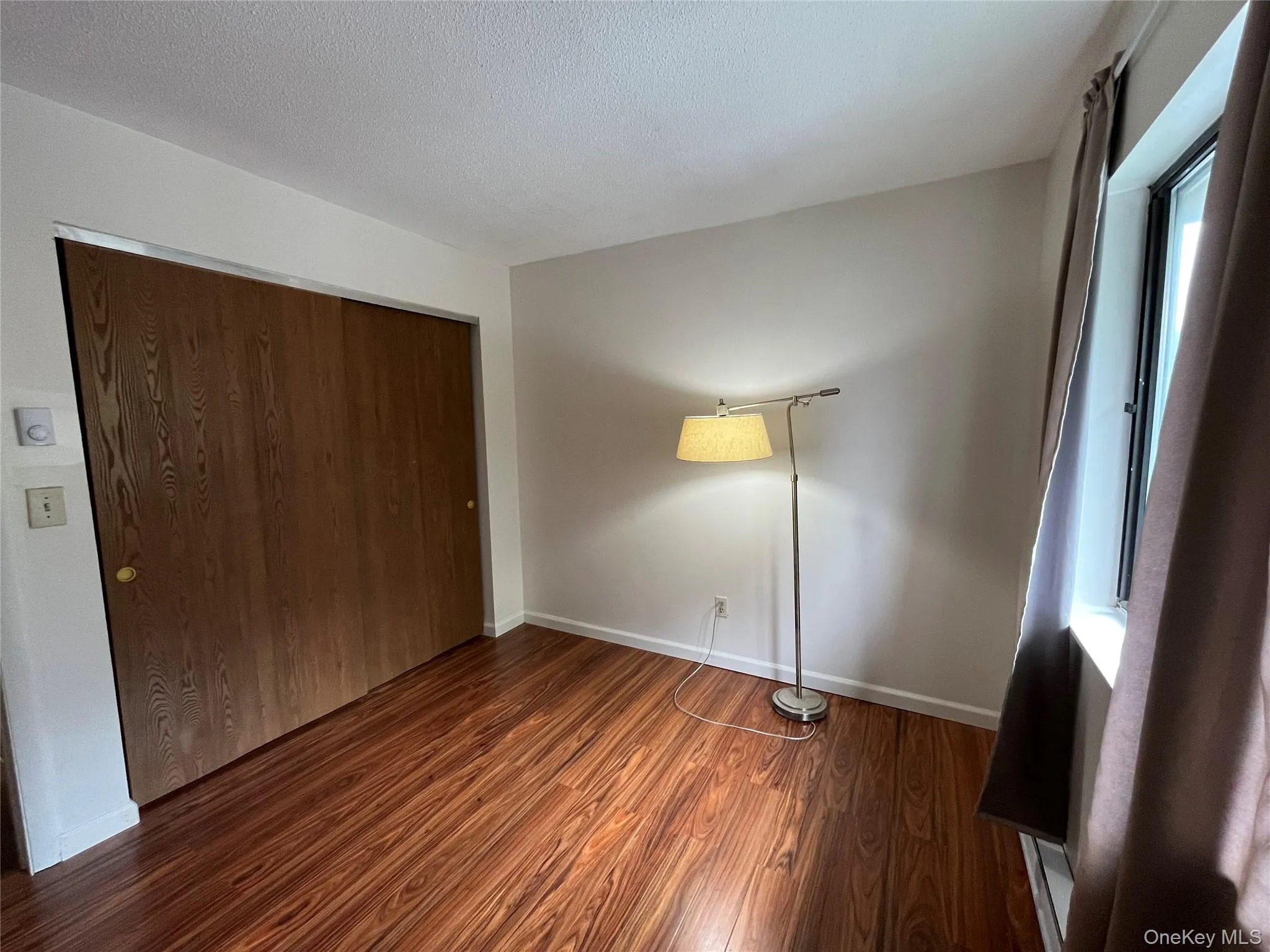 Unfurnished bedroom featuring wood finished floors, a closet, and a textured ceiling Unfurnished bedroom featuring wood finished floors, a closet, and a textured ceiling