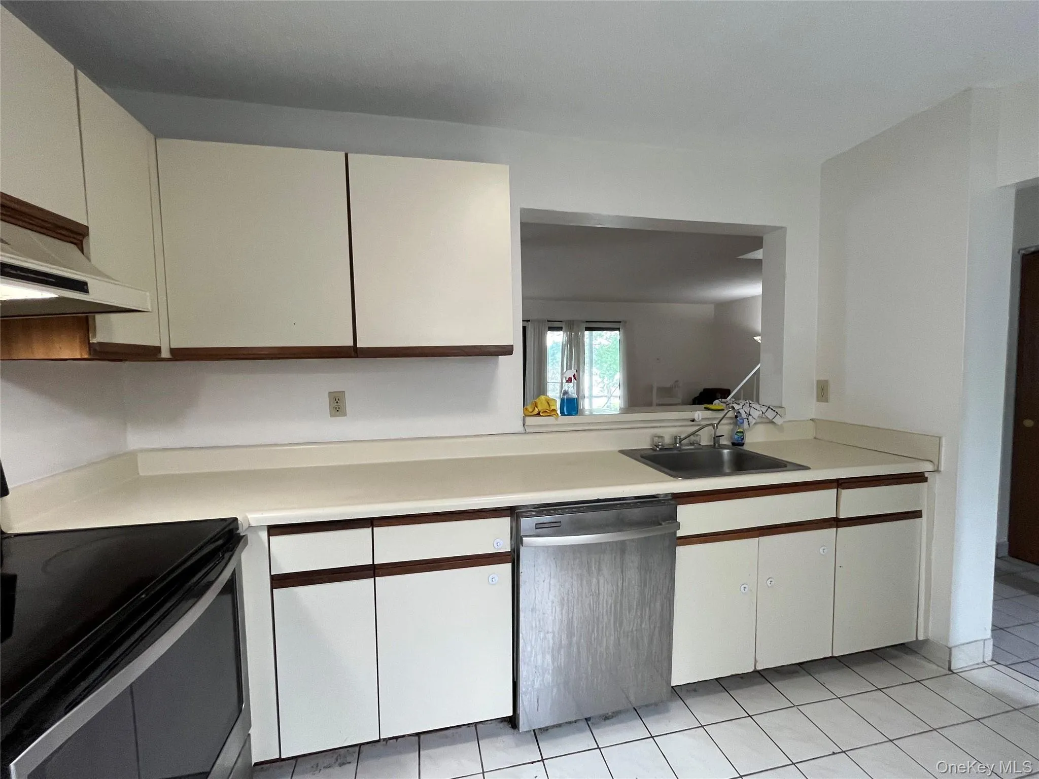 Kitchen with dishwasher, electric range, light countertops, light tile patterned floors, and white cabinetry Kitchen with dishwasher, electric range, light countertops, light tile patterned floors, and white cabinetry