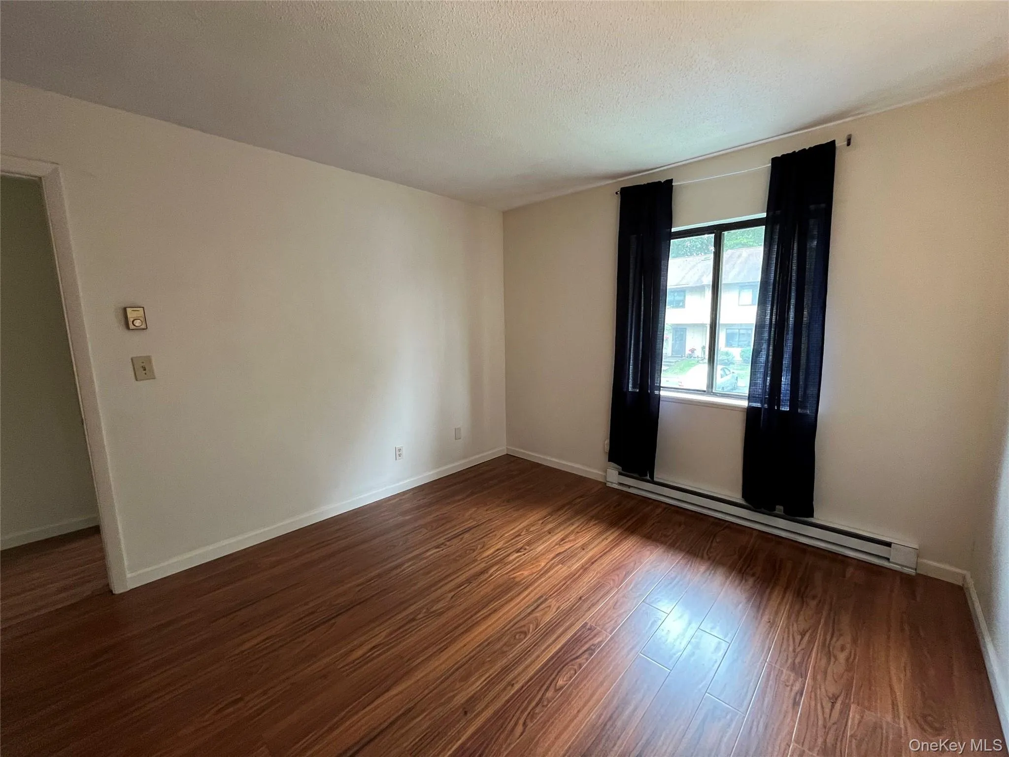 Spare room featuring baseboard heating and wood finished floors Spare room featuring baseboard heating and wood finished floors