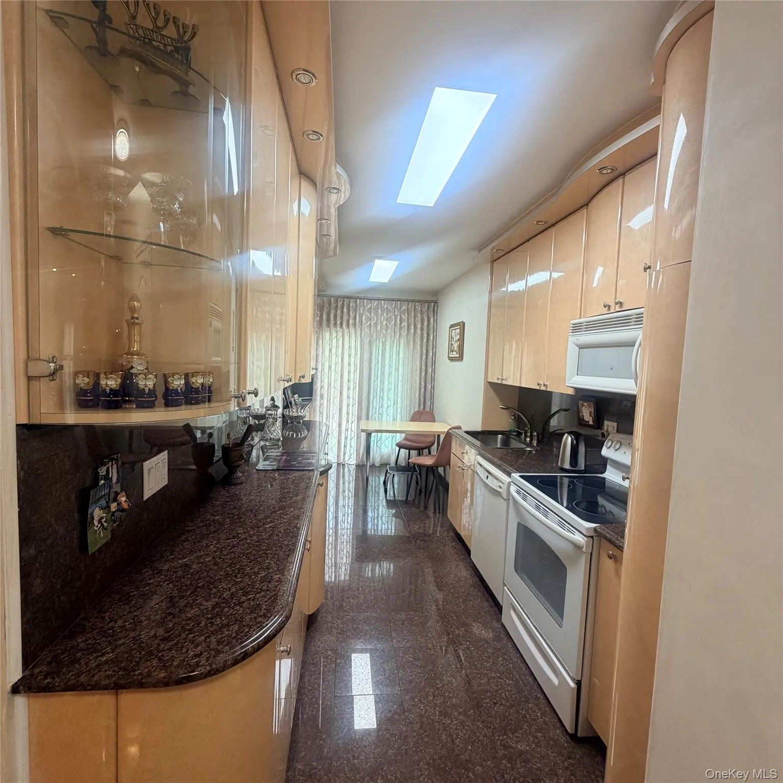 Galley kitchen featuring light wood-finish cabinetry, built-in appliances, and recessed lighting Galley kitchen featuring light wood-finish cabinetry, built-in appliances, and recessed lighting