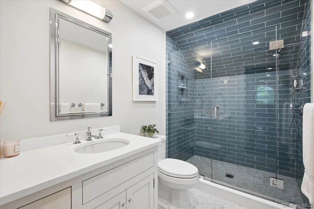 Beautiful bathroom featuring a glass-enclosed shower with blue subway tile surround and a white vanity Beautiful bathroom featuring a glass-enclosed shower with blue subway tile surround and a white vanity