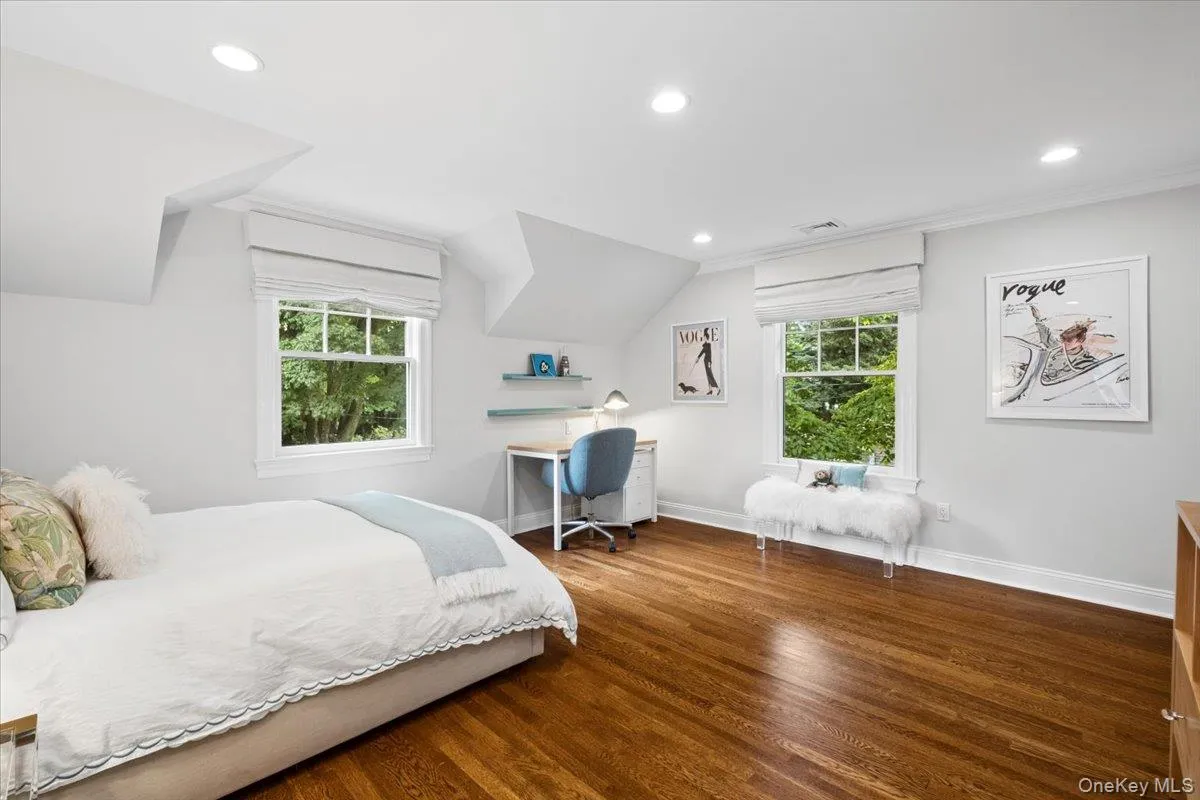 Hardwood flooring enhances this space featuring two windows with roman shades and recessed lighting Hardwood flooring enhances this space featuring two windows with roman shades and recessed lighting