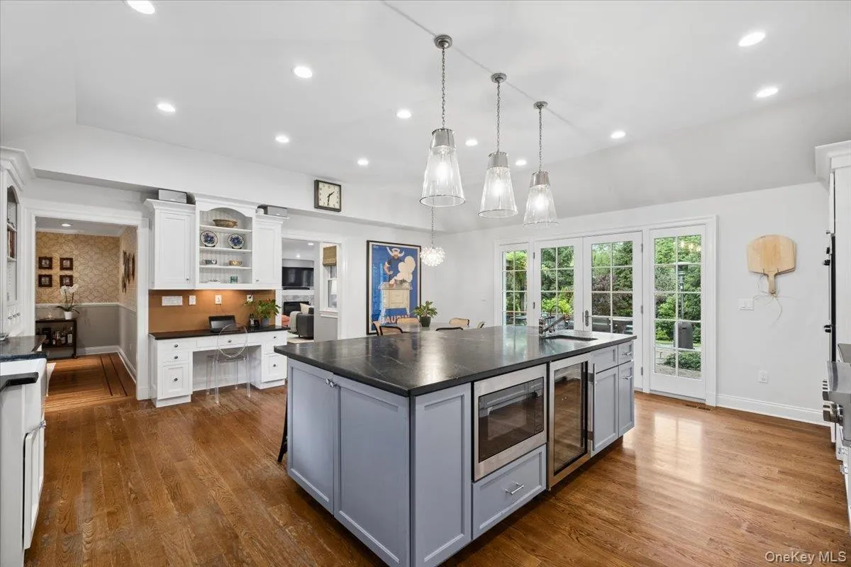 Spacious chef's kitchen featuring a large central island with top of the line appliances, hardwood flooring, and French doors leading out to the bluestone patio and private backyard Spacious chef's kitchen featuring a large central island with top of the line appliances, hardwood flooring, and French doors leading out to the bluestone patio and private backyard