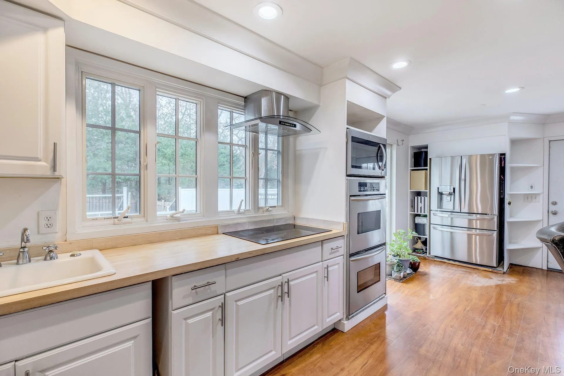 Kitchen featuring white cabinetry, wood-finish flooring, and recessed lighting Kitchen featuring white cabinetry, wood-finish flooring, and recessed lighting