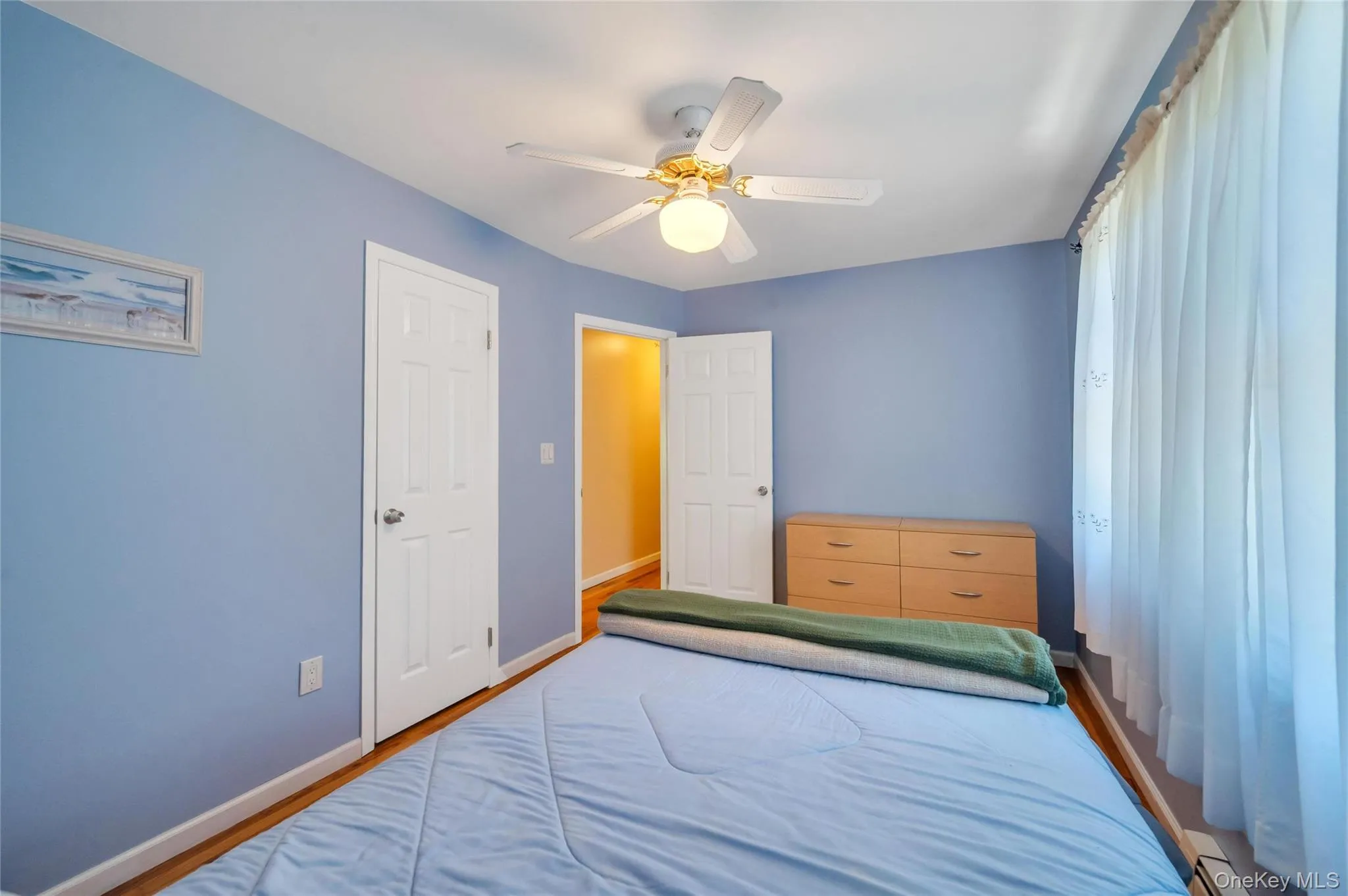 Bedroom featuring wood-finish flooring, a ceiling fan with integrated lighting, and white interior doors Bedroom featuring wood-finish flooring, a ceiling fan with integrated lighting, and white interior doors