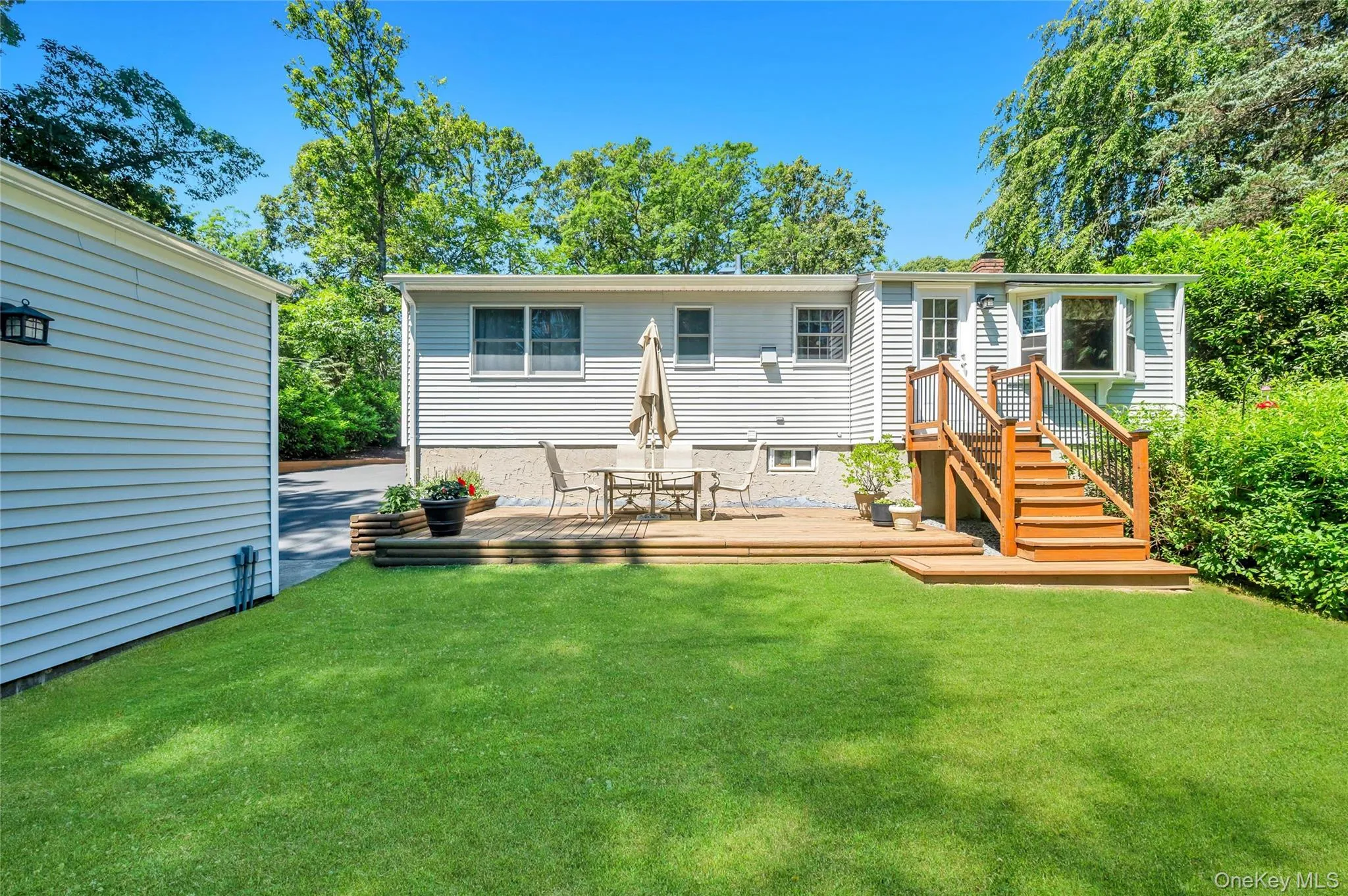 Back of home featuring stairs and a wood deck and side view of Garage Back of home featuring stairs and a wood deck and side view of Garage