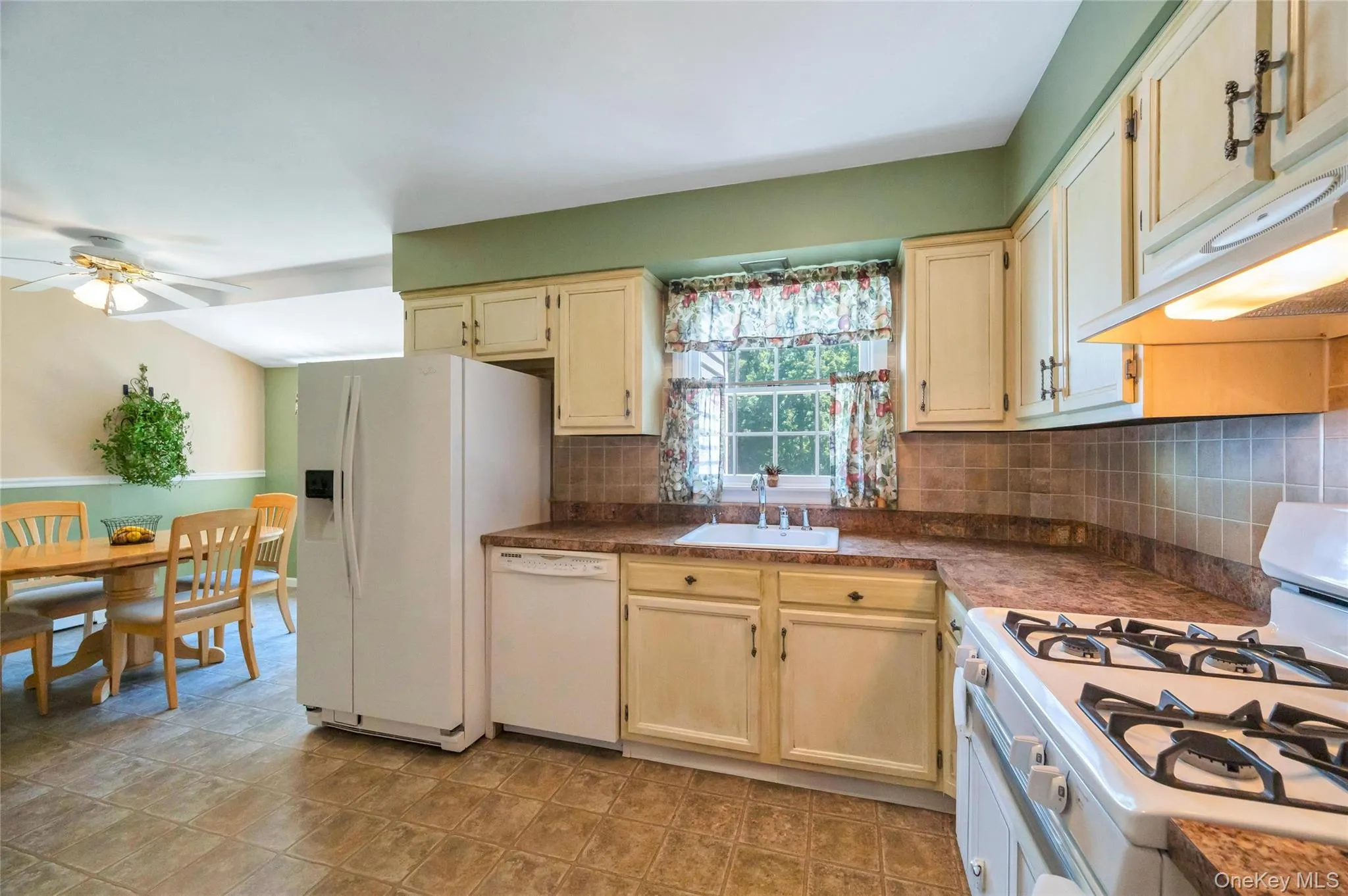 Kitchen featuring light-toned cabinetry, tile flooring, stone-look countertops, and a full tile backsplash Kitchen featuring light-toned cabinetry, tile flooring, stone-look countertops, and a full tile backsplash