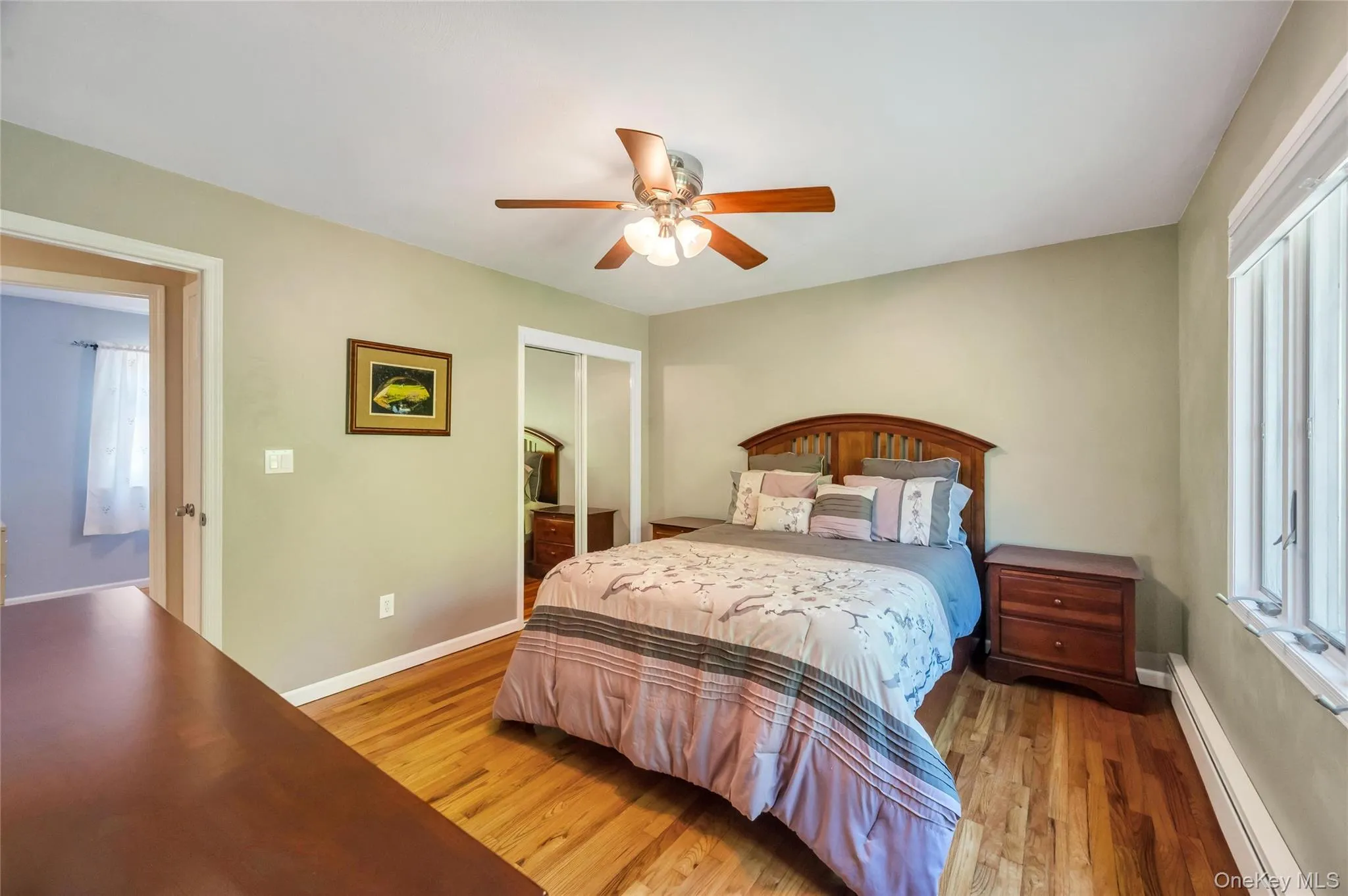 Bedroom featuring wood-finish flooring, a ceiling fan with integrated lighting, and a window with blinds Bedroom featuring wood-finish flooring, a ceiling fan with integrated lighting, and a window with blinds