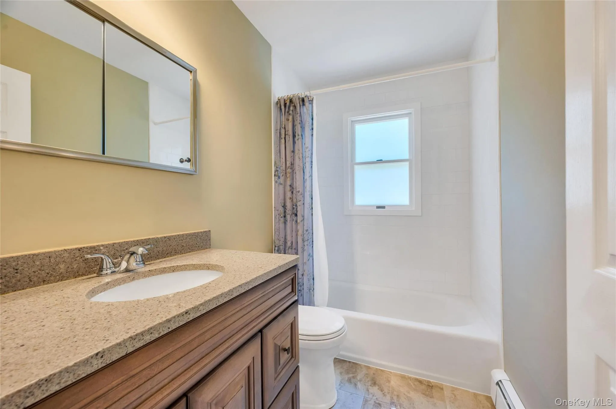 Bathroom featuring a wood-finish vanity with a light-toned countertop, an undermount sink, and a mirrored medicine cabinet Bathroom featuring a wood-finish vanity with a light-toned countertop, an undermount sink, and a mirrored medicine cabinet