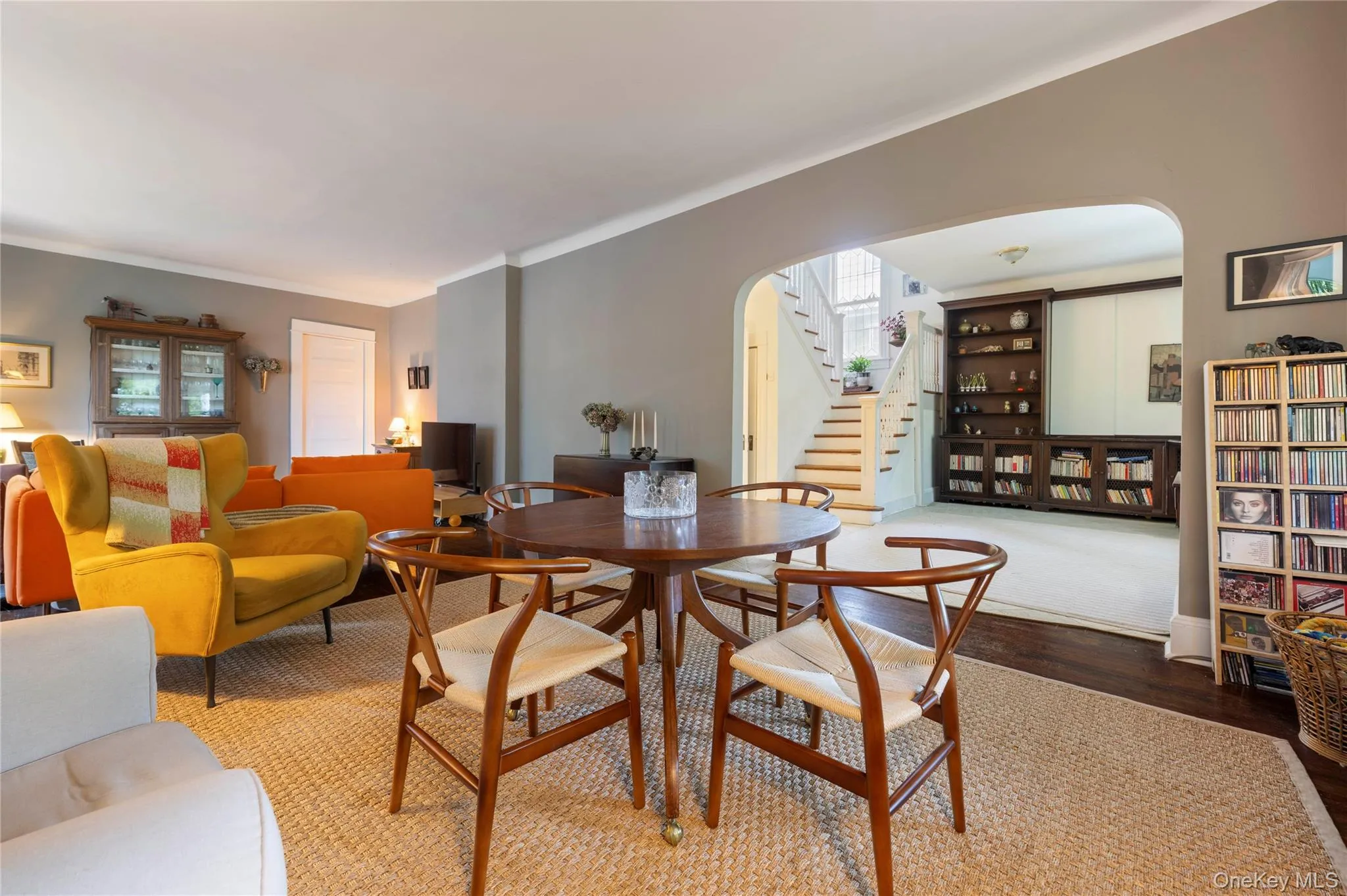 Open-concept living space featuring a natural fiber area rug, an arched doorway, and built-in shelving Open-concept living space featuring a natural fiber area rug, an arched doorway, and built-in shelving
