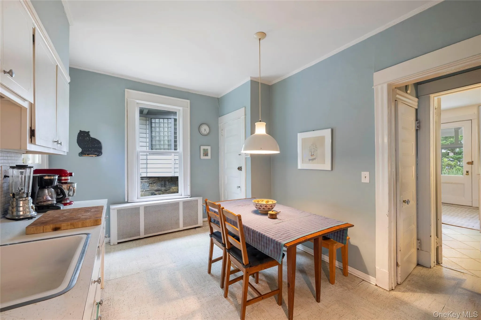 Kitchen featuring white cabinetry, a single basin sink, and a window with a radiator below Kitchen featuring white cabinetry, a single basin sink, and a window with a radiator below