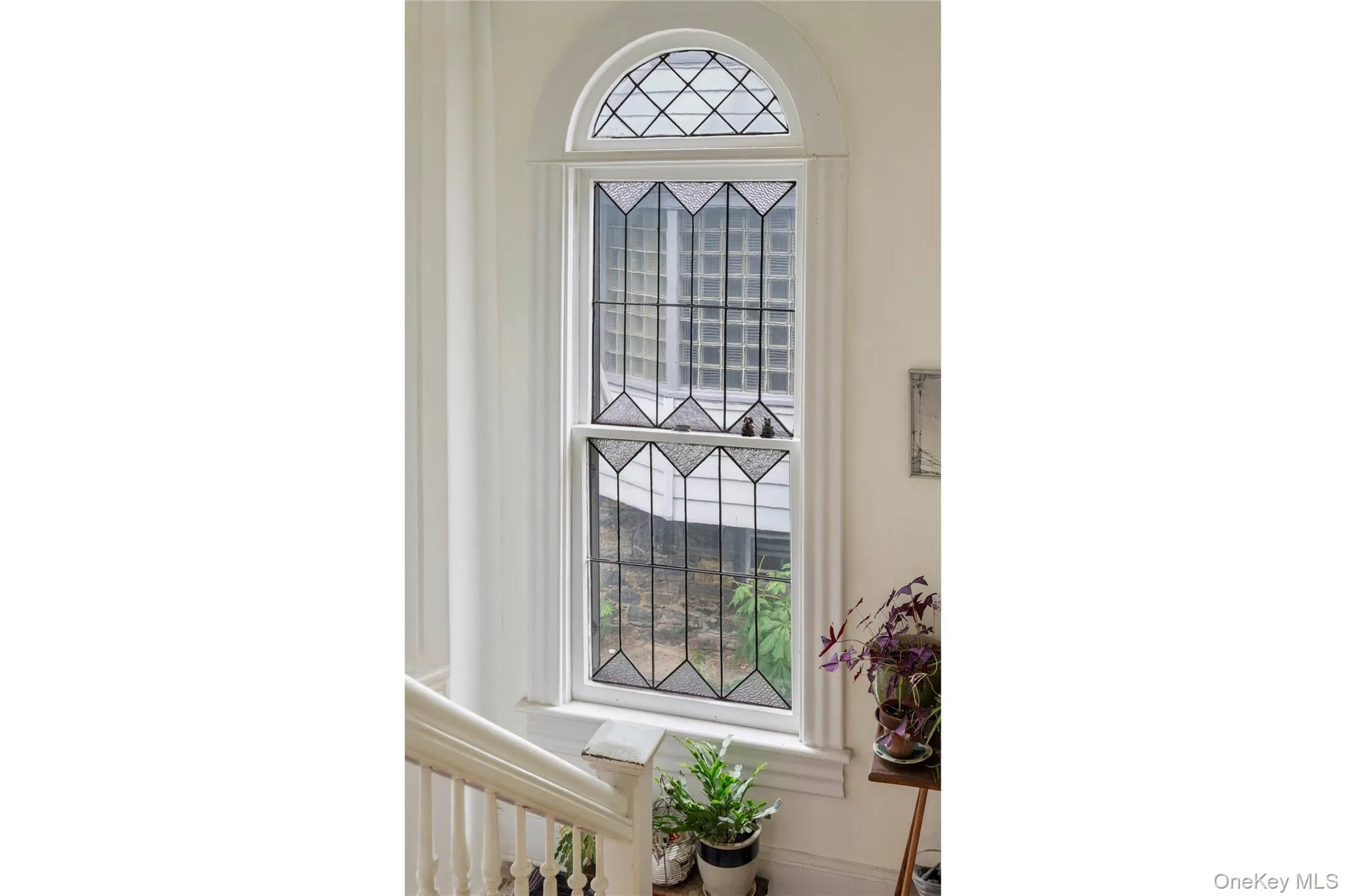 Arched window featuring leaded glass panels and white trim Arched window featuring leaded glass panels and white trim