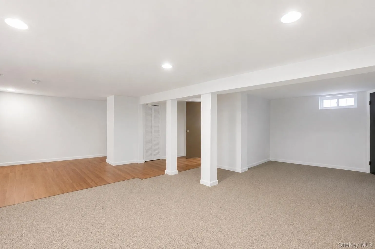 Finished basement featuring recessed lighting, a combination of wood-finish flooring and carpeting, white painted walls, and egress door Finished basement featuring recessed lighting, a combination of wood-finish flooring and carpeting, white painted walls, and egress door