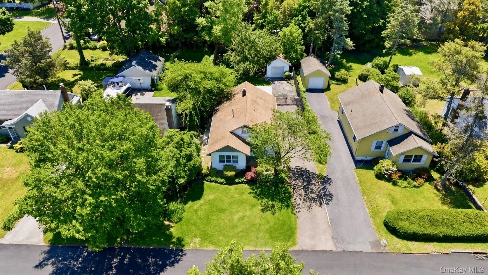 Residential property featuring a detached garage, expansive driveway, and beautiful landscaping Residential property featuring a detached garage, expansive driveway, and beautiful landscaping