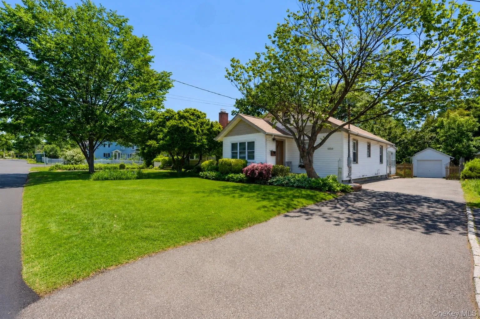 White exterior with a pitched roof, front landscaping, and an asphalt driveway White exterior with a pitched roof, front landscaping, and an asphalt driveway