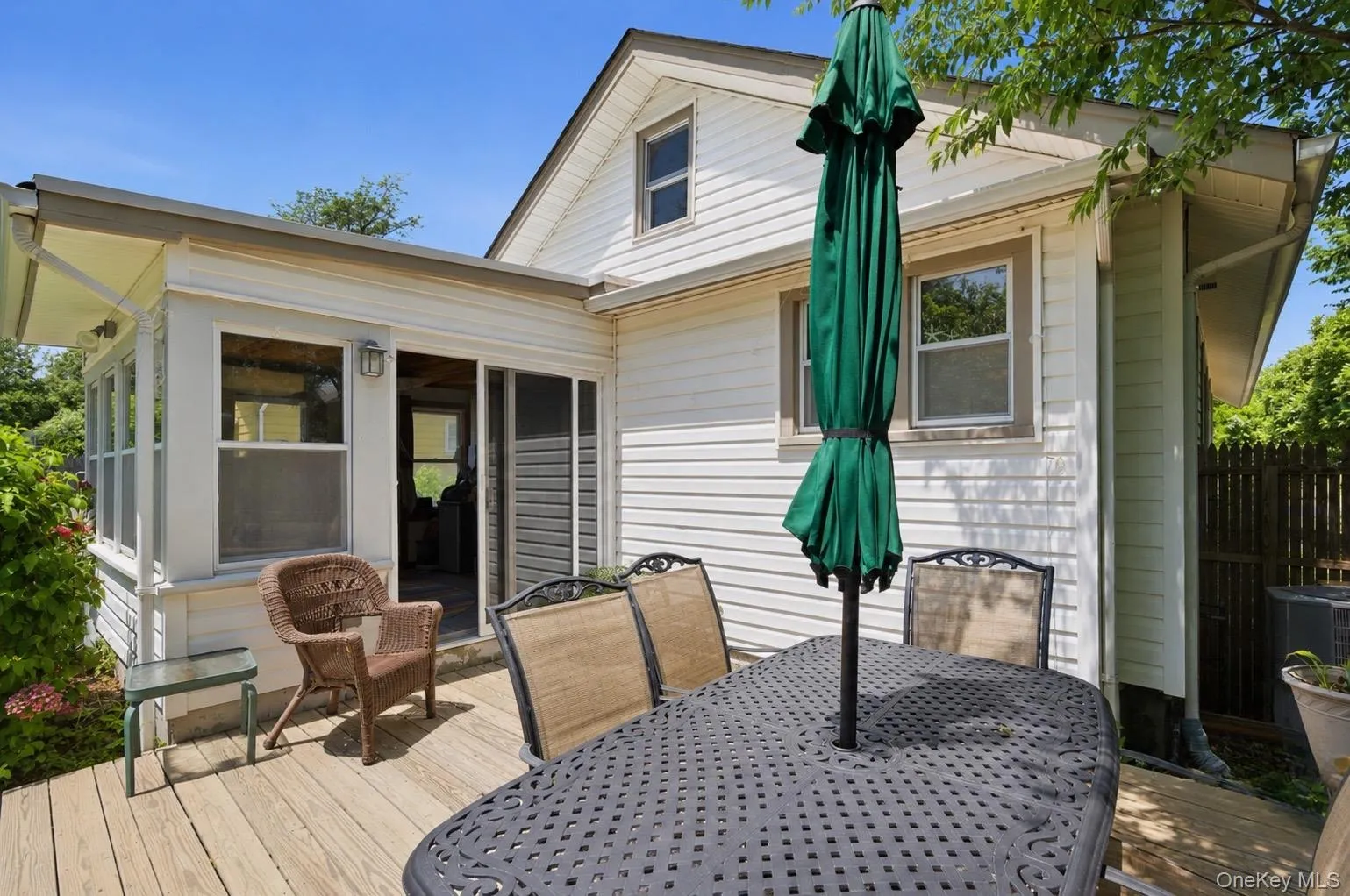Expansive wood deck with a screened-in porch and white siding exterior Expansive wood deck with a screened-in porch and white siding exterior