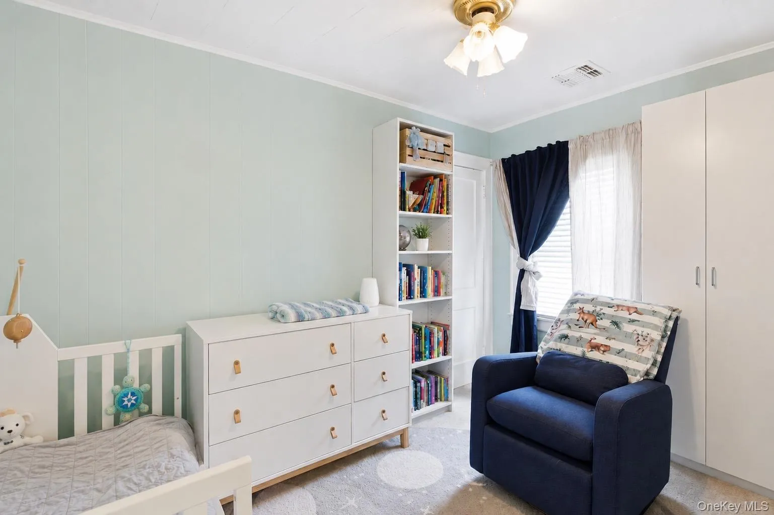 Room featuring wainscoting walls, a flush-mount ceiling light fixture, and a built-in white wardrobe Room featuring wainscoting walls, a flush-mount ceiling light fixture, and a built-in white wardrobe