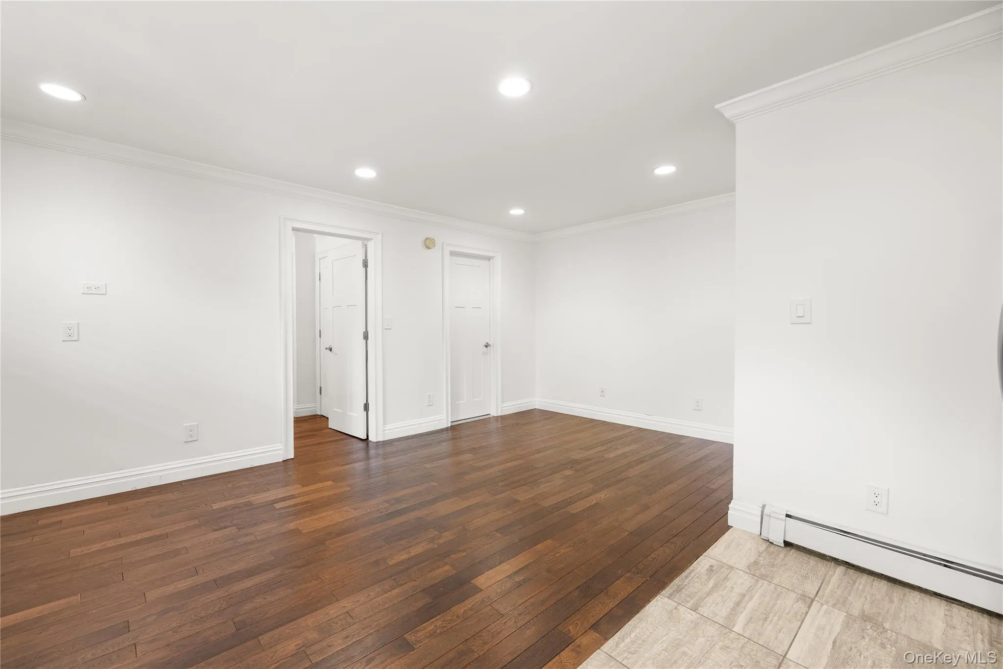Living room featuring hardwood flooring, an AC wall unit, baseboard heating and a beautiful open floor plan Living room featuring hardwood flooring, an AC wall unit, baseboard heating and a beautiful open floor plan