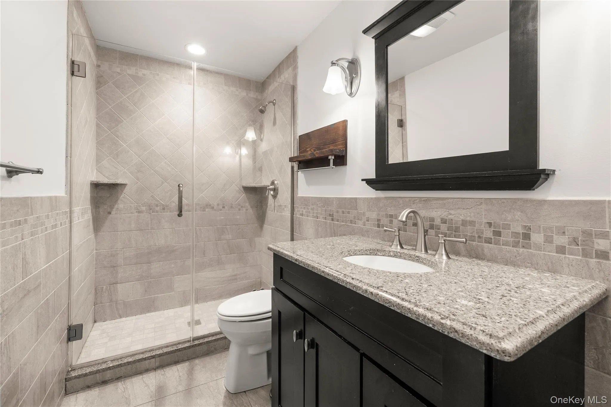 Bathroom with updated shower stall, vanity, half tile walls, mosaic, and tasteful finishes Bathroom with updated shower stall, vanity, half tile walls, mosaic, and tasteful finishes
