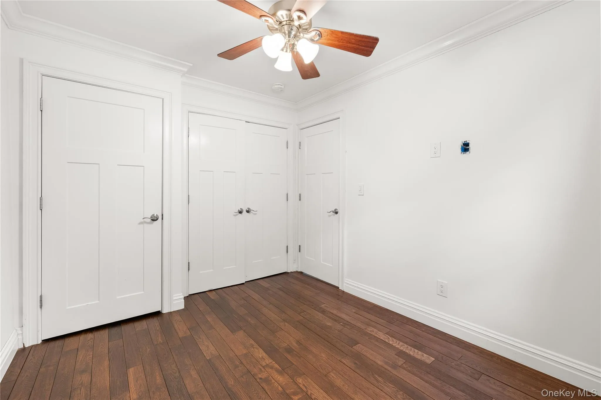 Unfurnished bedroom featuring hardwood flooring and his and her closets Unfurnished bedroom featuring hardwood flooring and his and her closets
