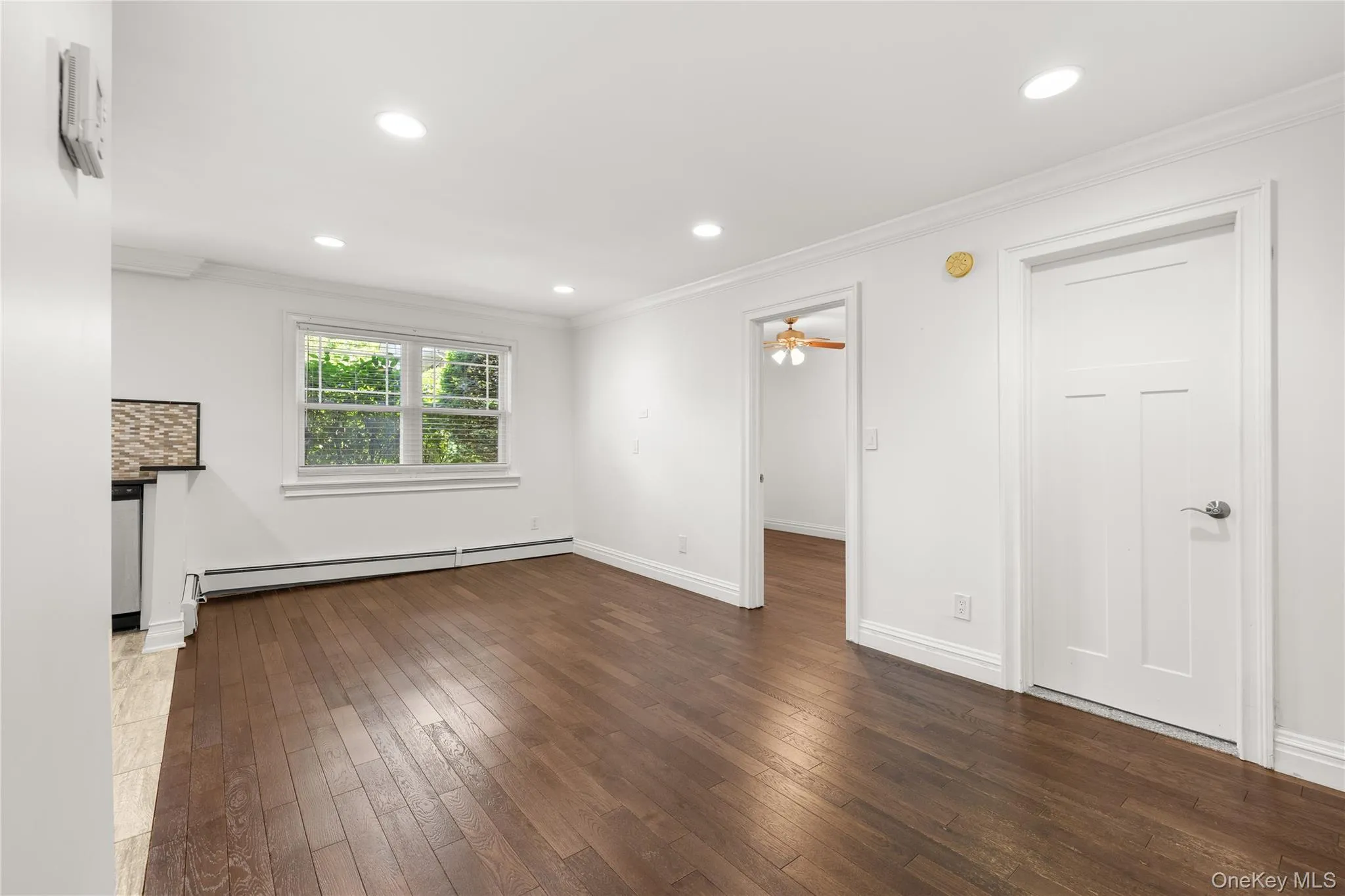 Living room featuring hardwood flooring, an AC wall unit, baseboard heating and a beautiful open floor plan Living room featuring hardwood flooring, an AC wall unit, baseboard heating and a beautiful open floor plan