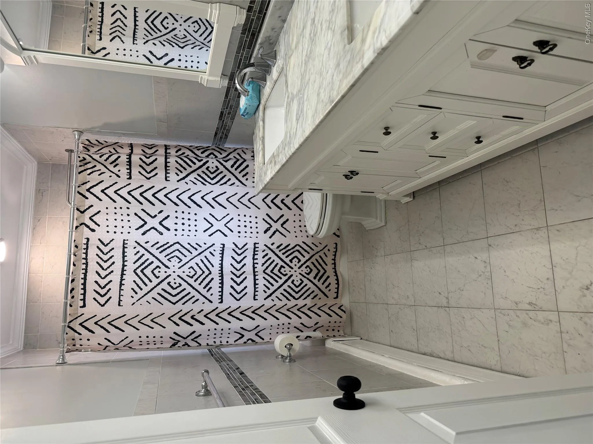 Bathroom featuring a white vanity with a stone countertop, an undermount sink, and black hardware Bathroom featuring a white vanity with a stone countertop, an undermount sink, and black hardware