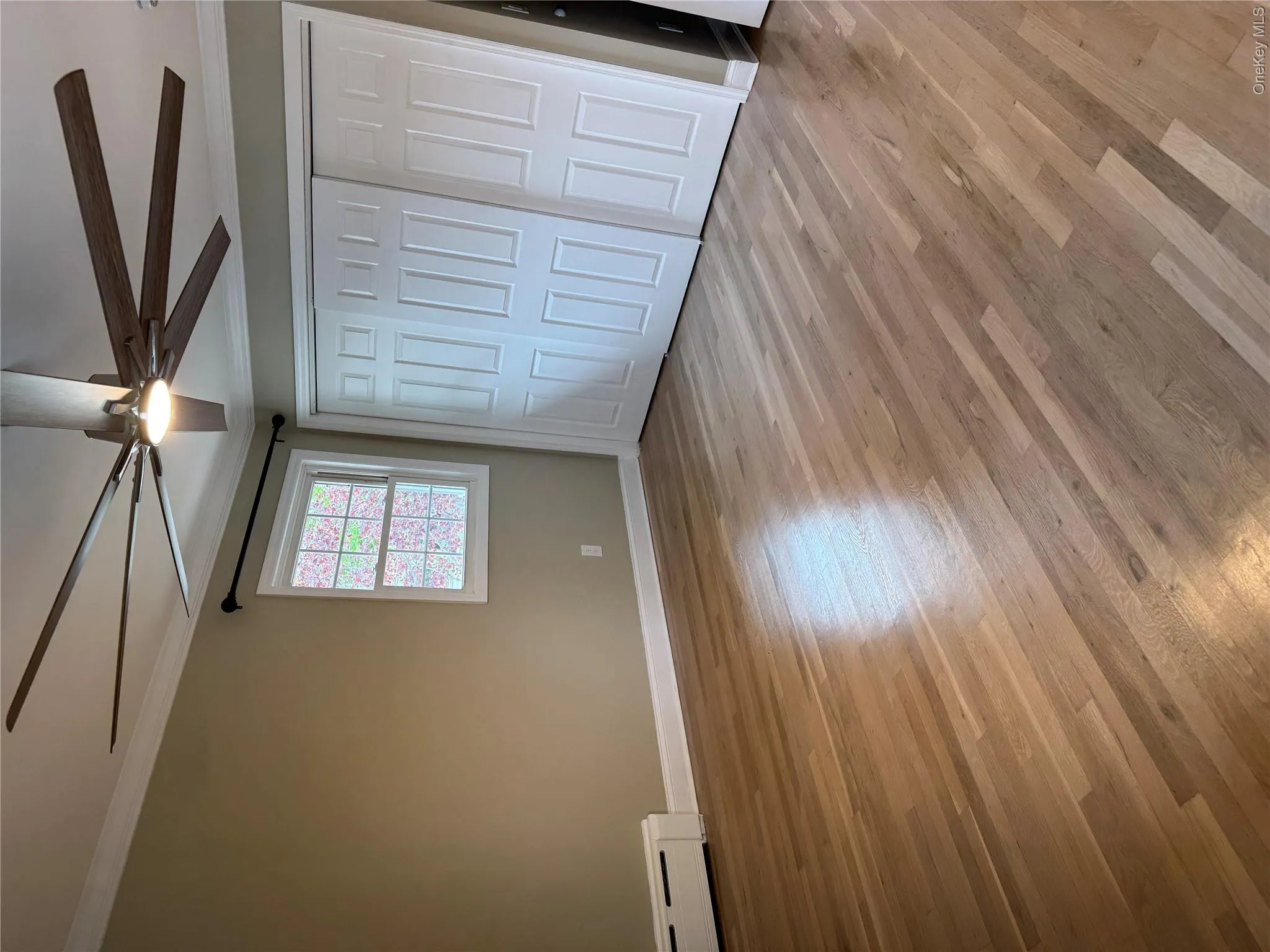 Refinished wood flooring showcasing a modern ceiling fan with integrated lighting, crown molding, and bi-fold closet doors Refinished wood flooring showcasing a modern ceiling fan with integrated lighting, crown molding, and bi-fold closet doors