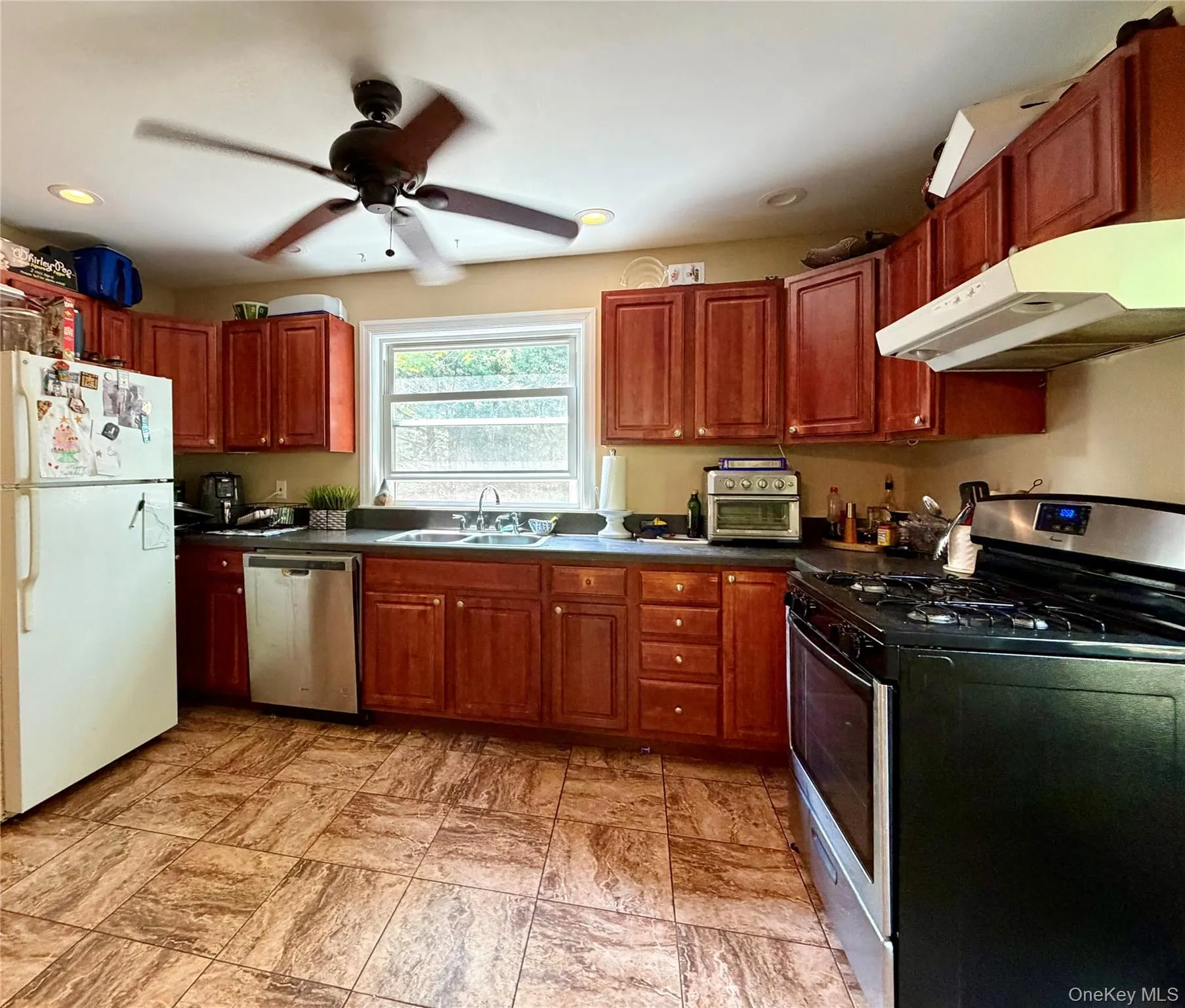 Kitchen featuring wood cabinetry, dark countertops, and tile flooring Kitchen featuring wood cabinetry, dark countertops, and tile flooring