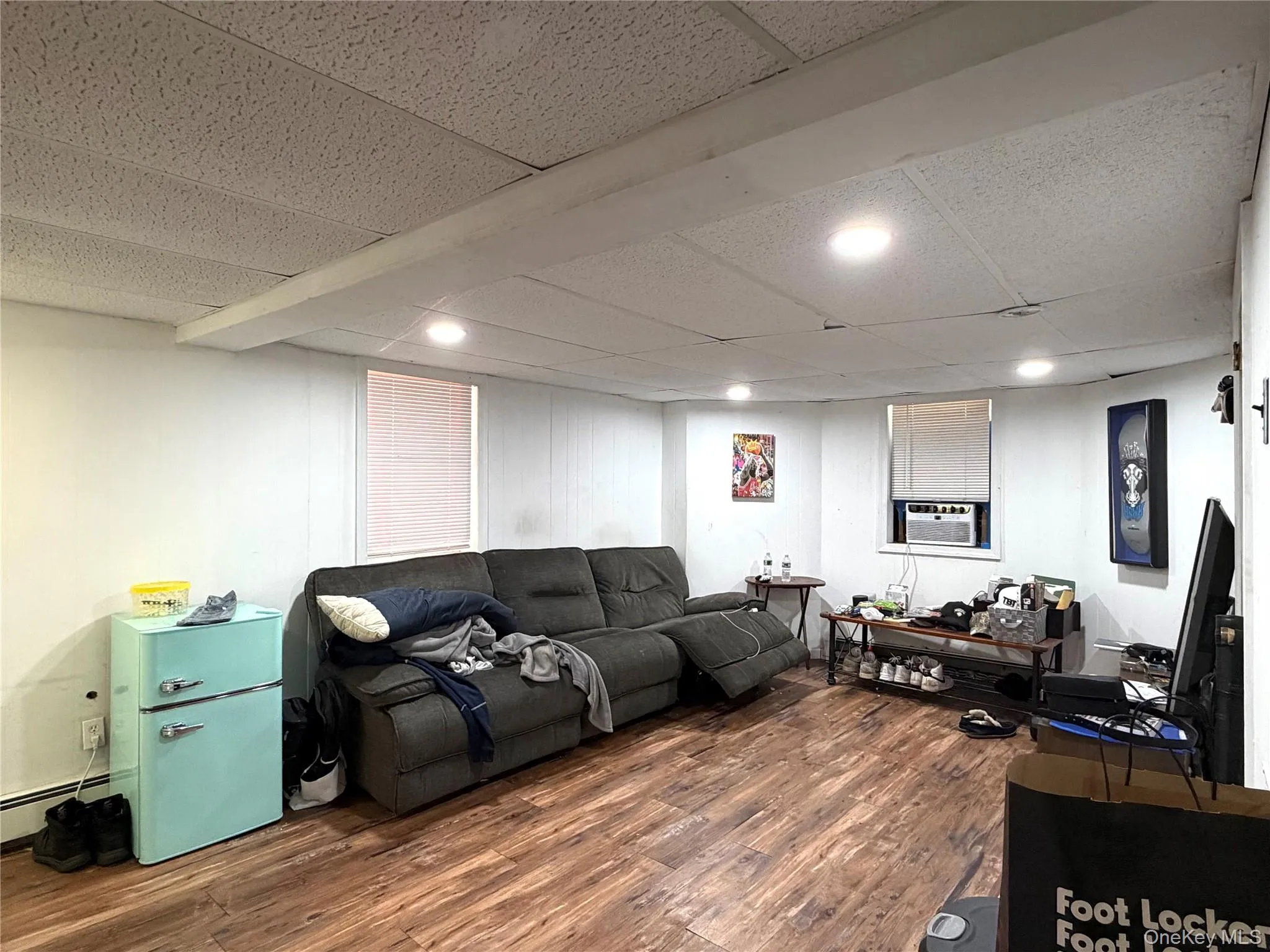 Finished room in basement featuring flooring, white paneled walls, and a dropped ceiling with recessed lighting Finished room in basement featuring flooring, white paneled walls, and a dropped ceiling with recessed lighting
