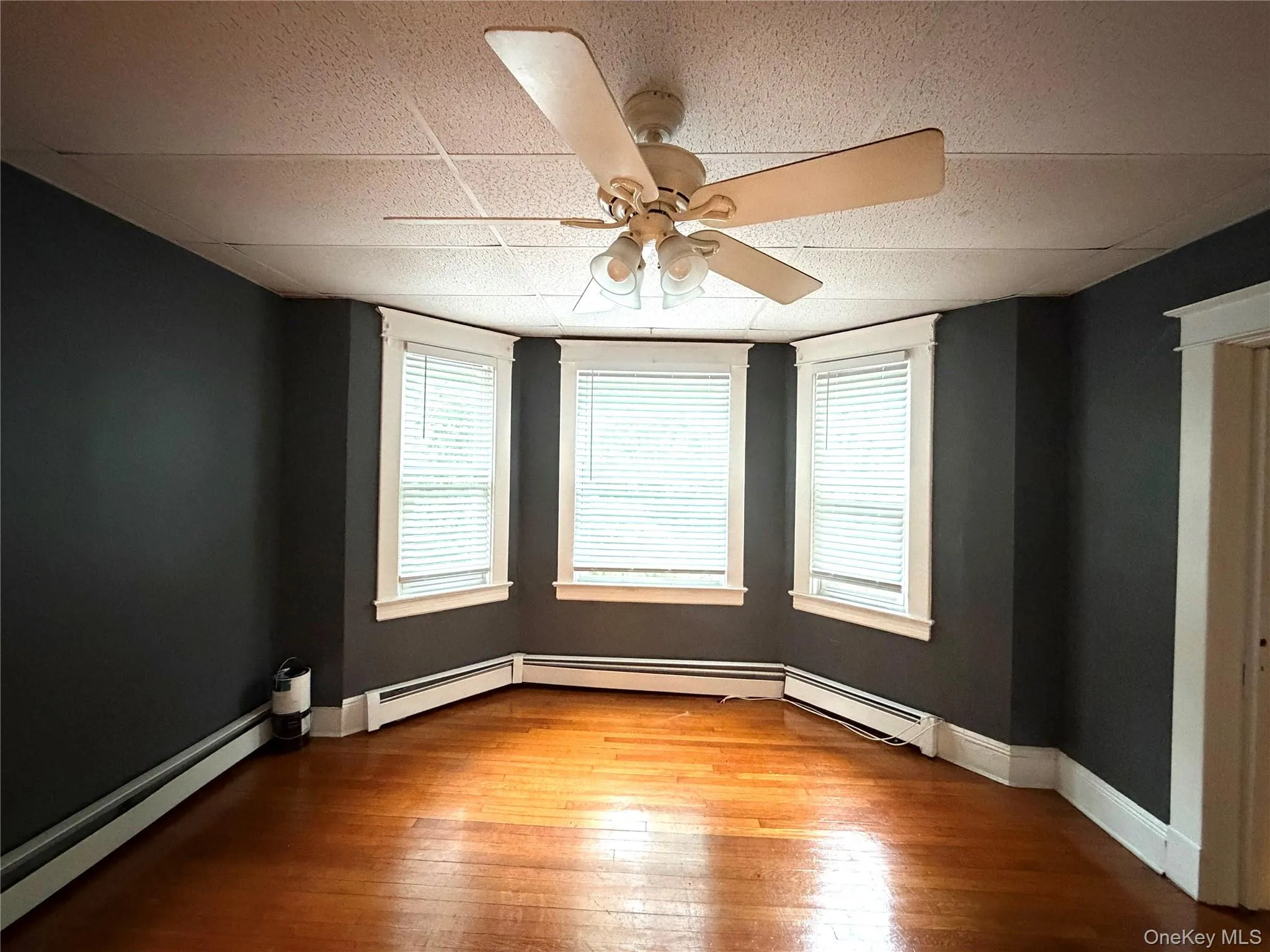 Bay window with three windows, hardwood flooring, and ceiling fan with integrated lighting Bay window with three windows, hardwood flooring, and ceiling fan with integrated lighting