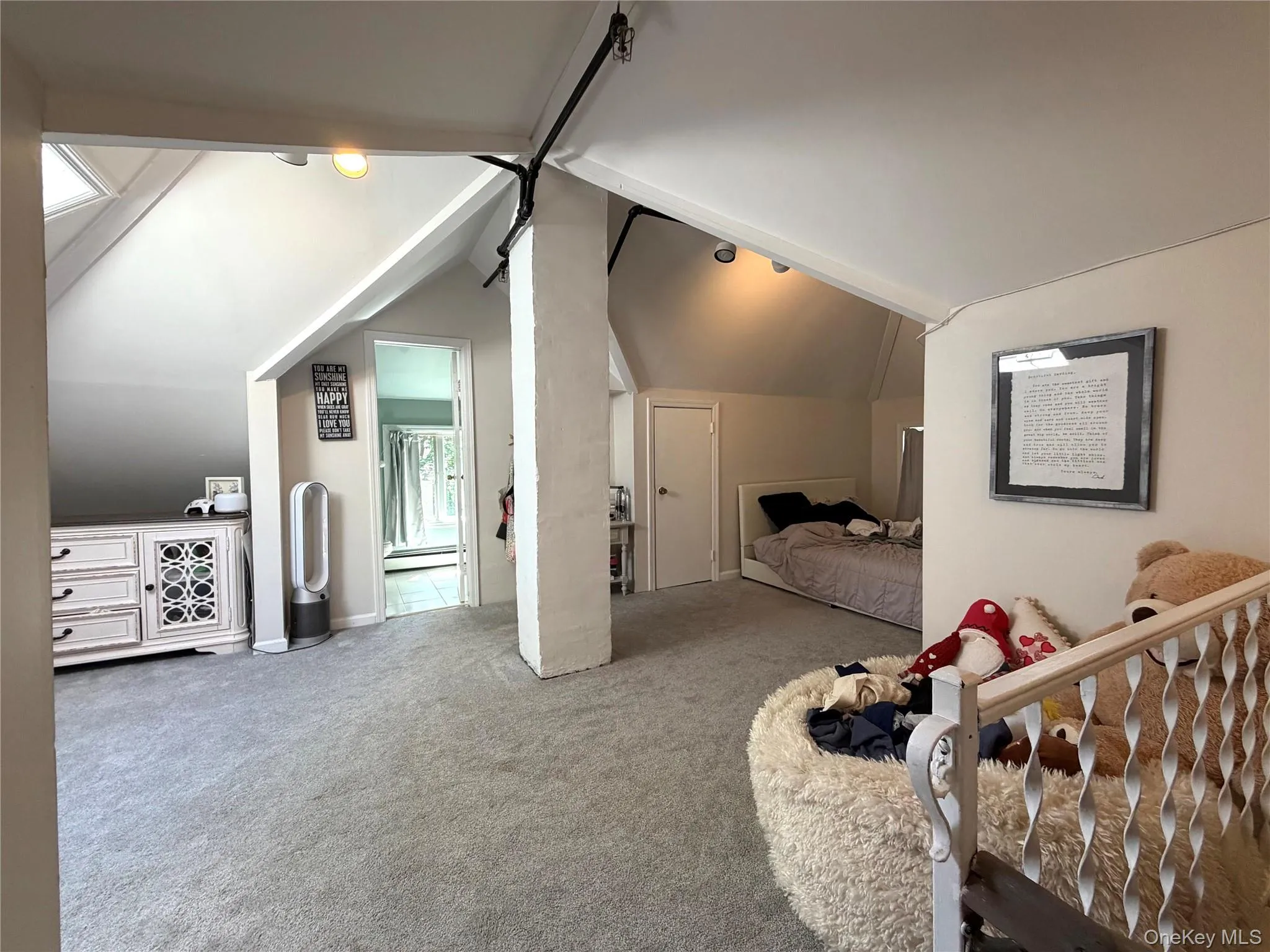 Carpeted attic space featuring sloped ceilings, white painted walls, and an exposed structural beam Carpeted attic space featuring sloped ceilings, white painted walls, and an exposed structural beam