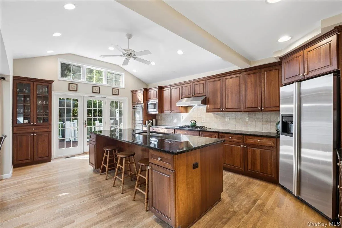 Sun-filled kitchen with custom cabinetry and stainless steel appliances with doors to expansive deck Sun-filled kitchen with custom cabinetry and stainless steel appliances with doors to expansive deck